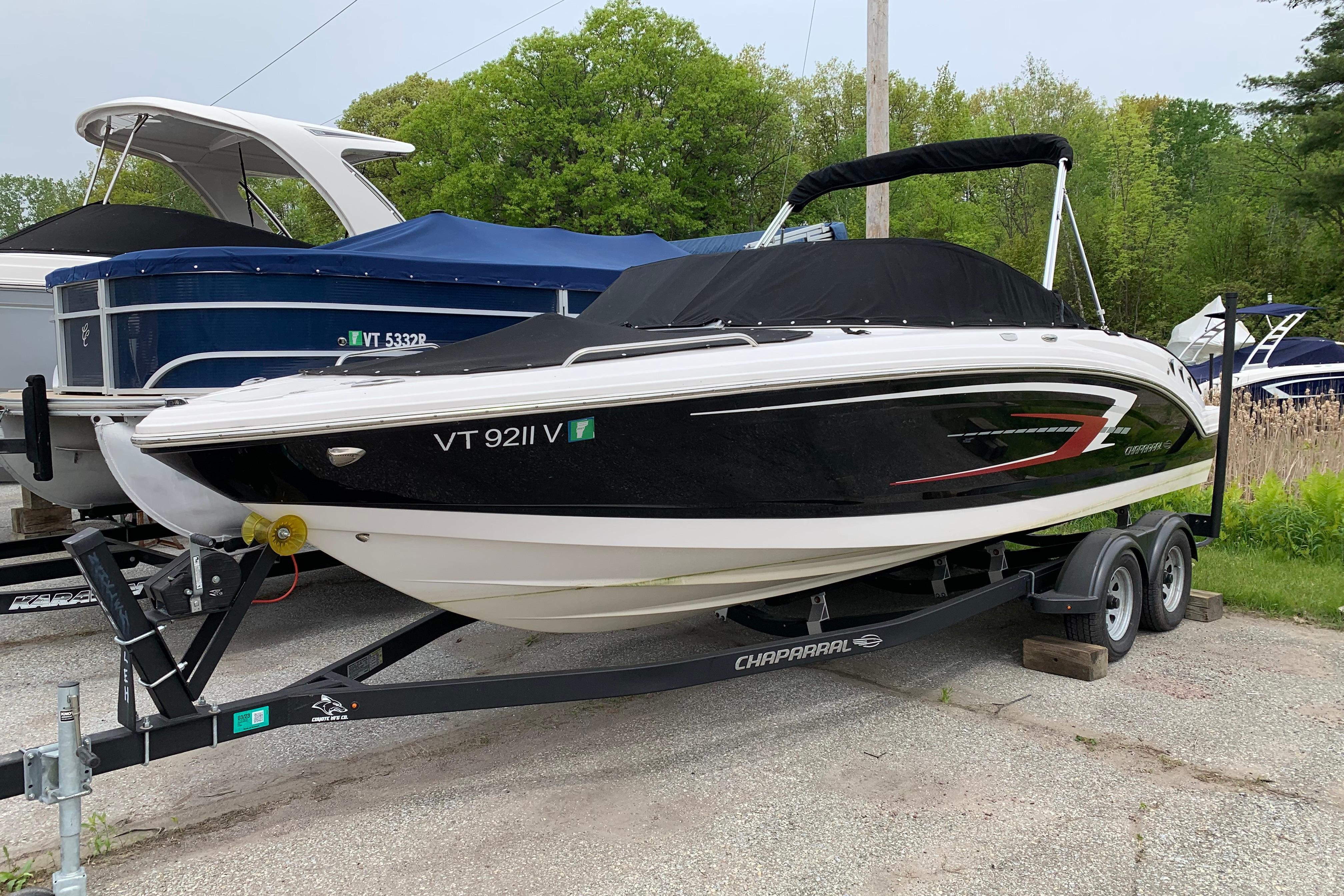 2022 Chaparral 23 SSi boat on trailer, black and white design, parked outdoors.