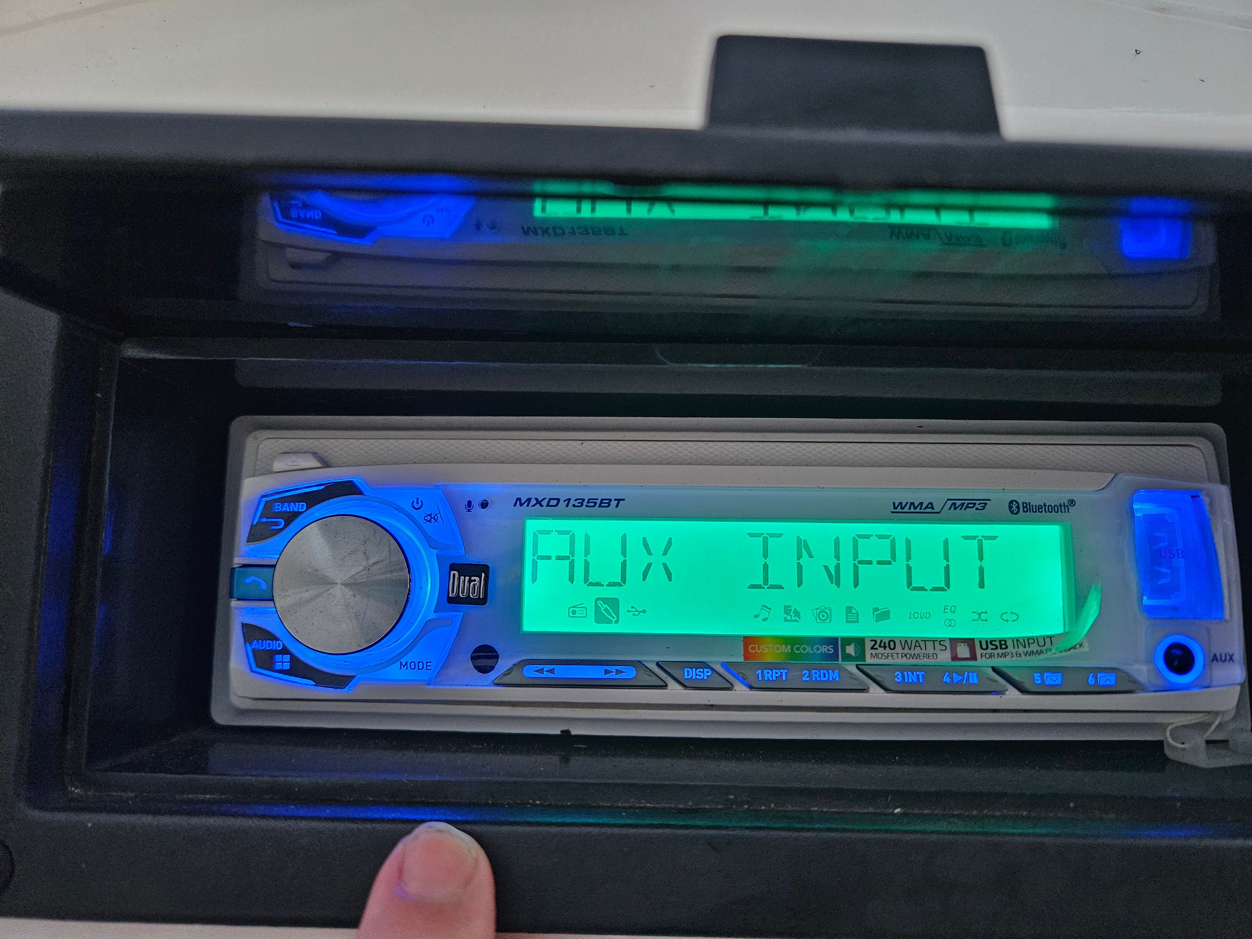 A modern car stereo with AUX input and Bluetooth capability.