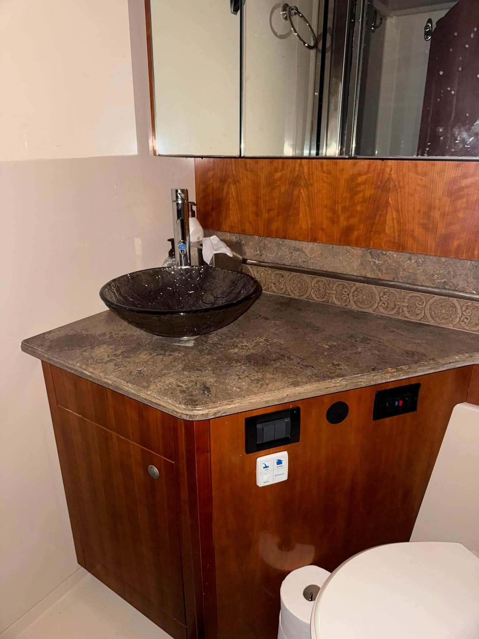 The image shows a yacht bathroom with a modern sink and wooden cabinetry.