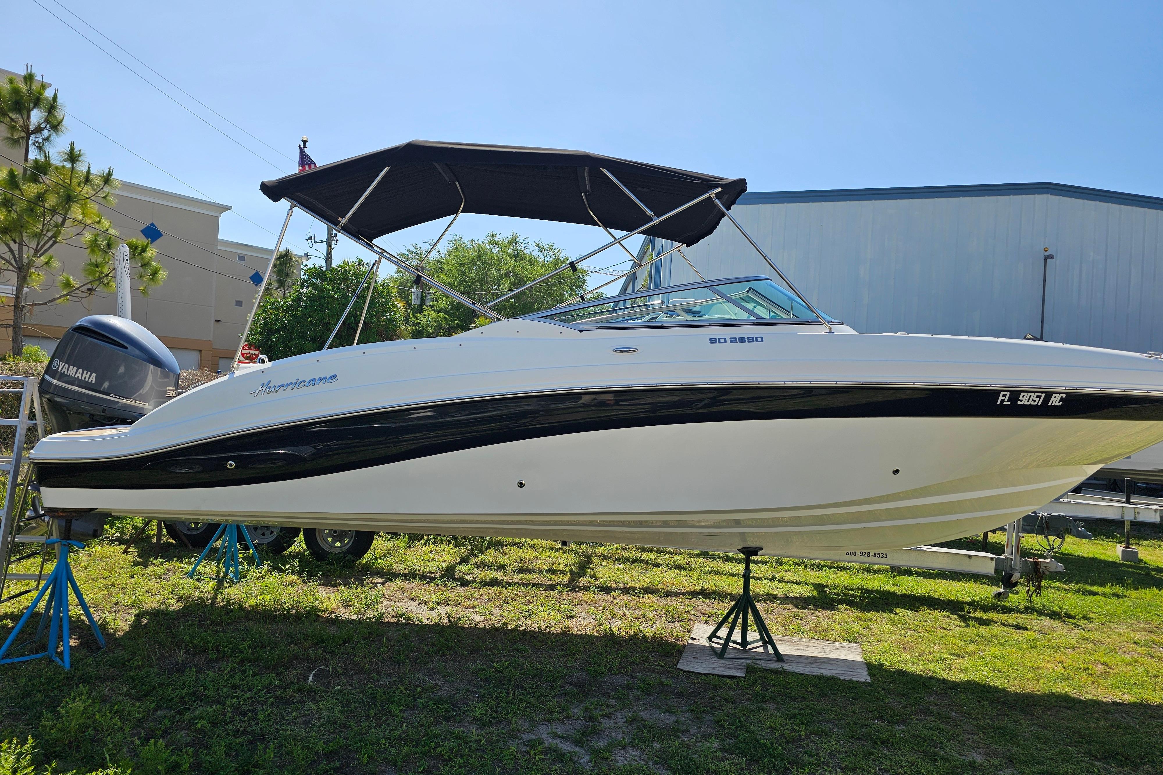 2016 Hurricane SunDeck 2690 OB boat with canopy on display outdoors.