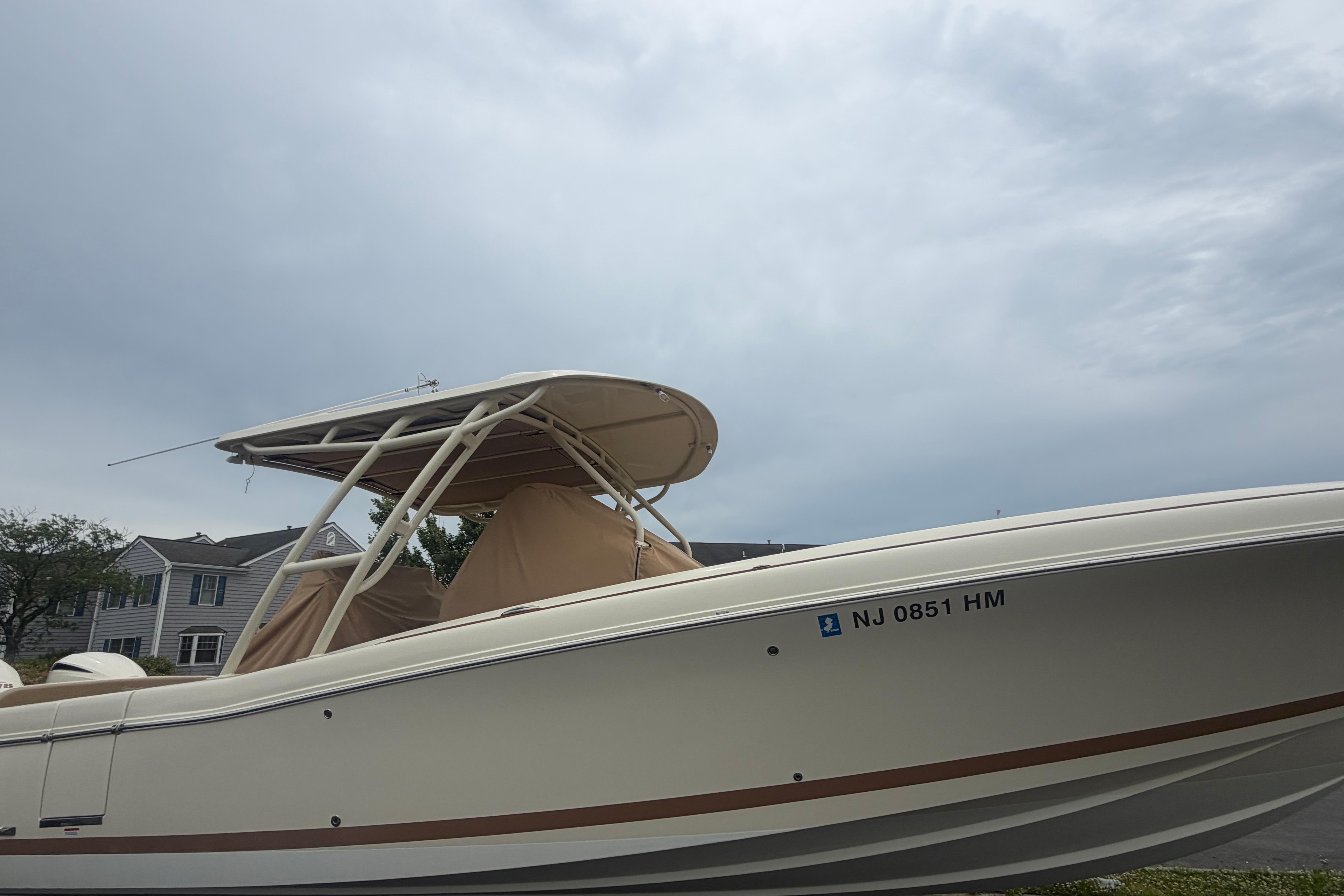 2017 Chris-Craft Catalina 34 boat with canopy, parked in a residential area under cloudy skies.
