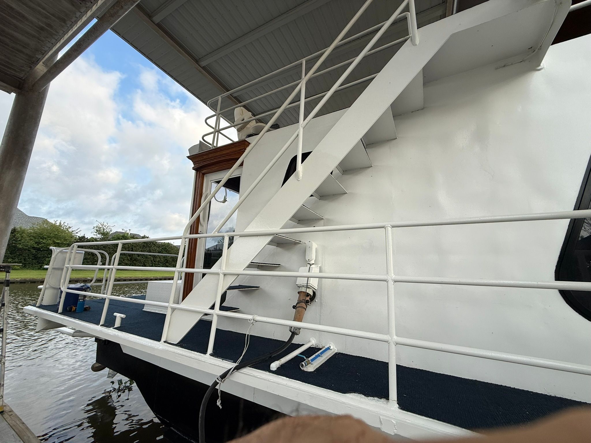A white boat with a side staircase, docked at a pier.