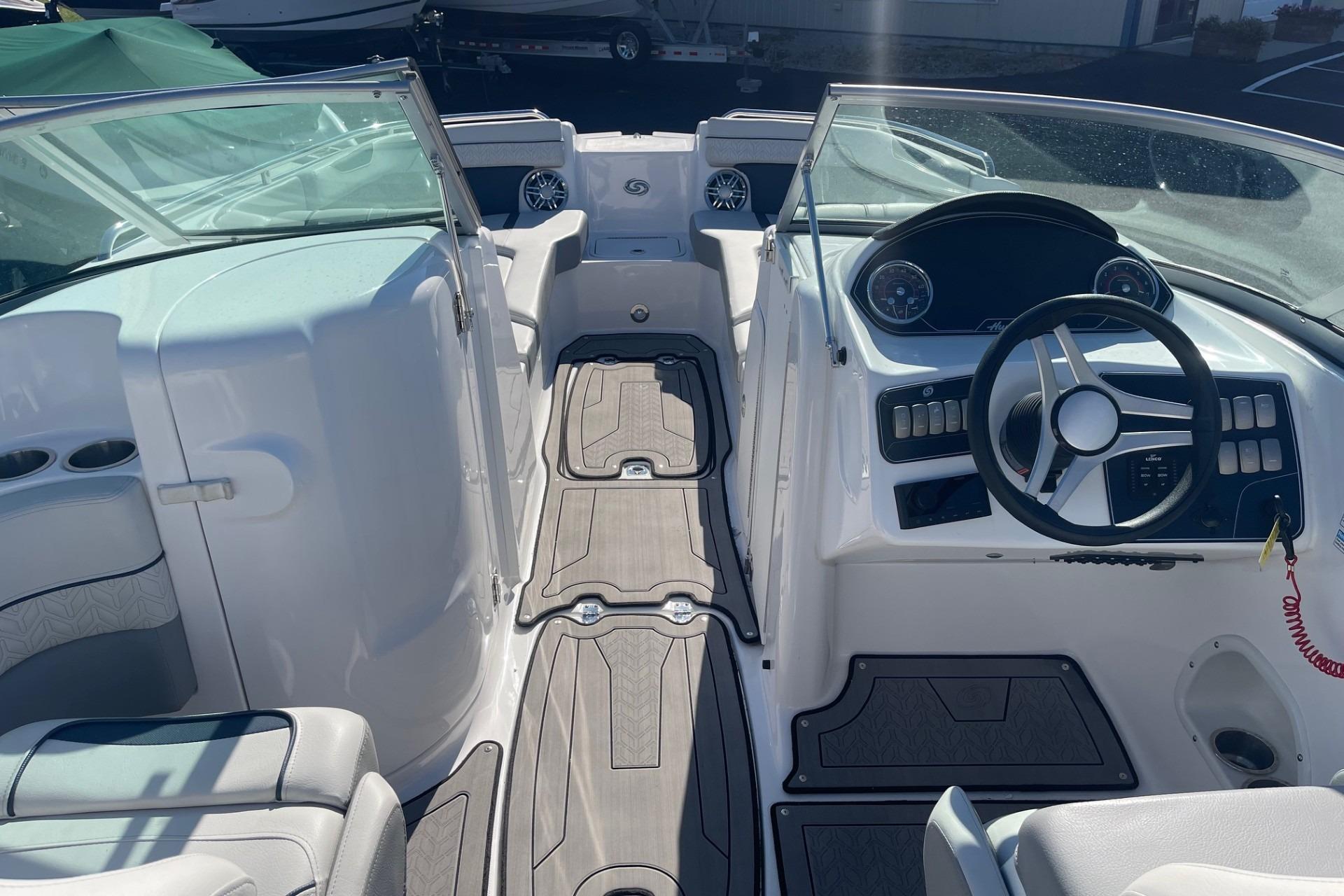 2023 Hurricane SunDeck 2400 OB boat interior with steering wheel and seating area.