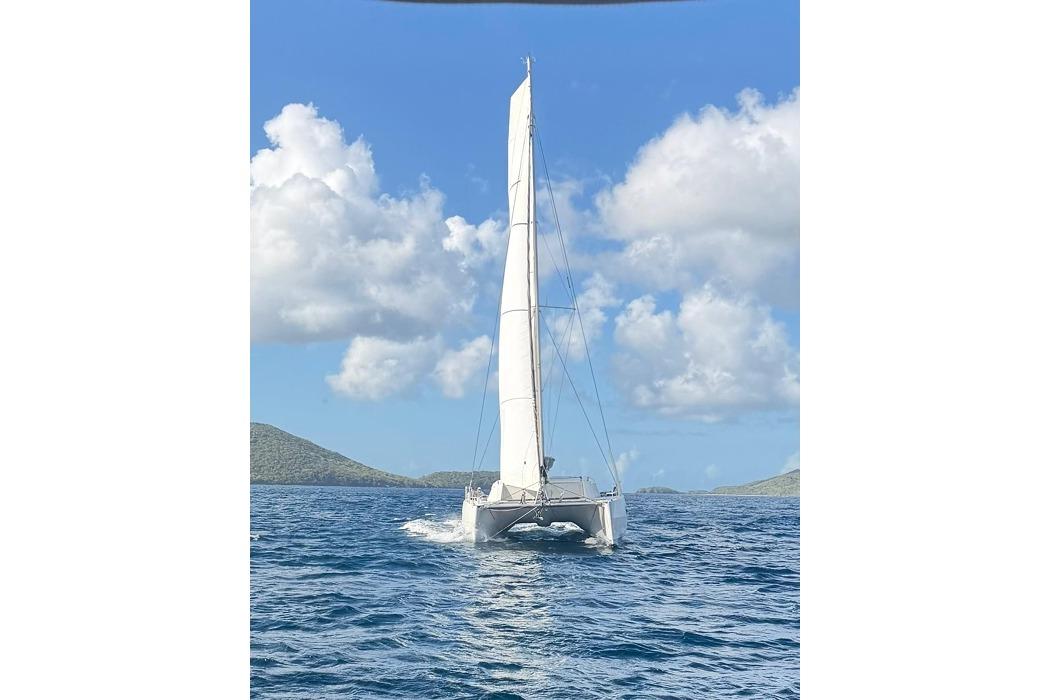 2021 Catana 53 sailing catamaran on open sea under clear blue sky.