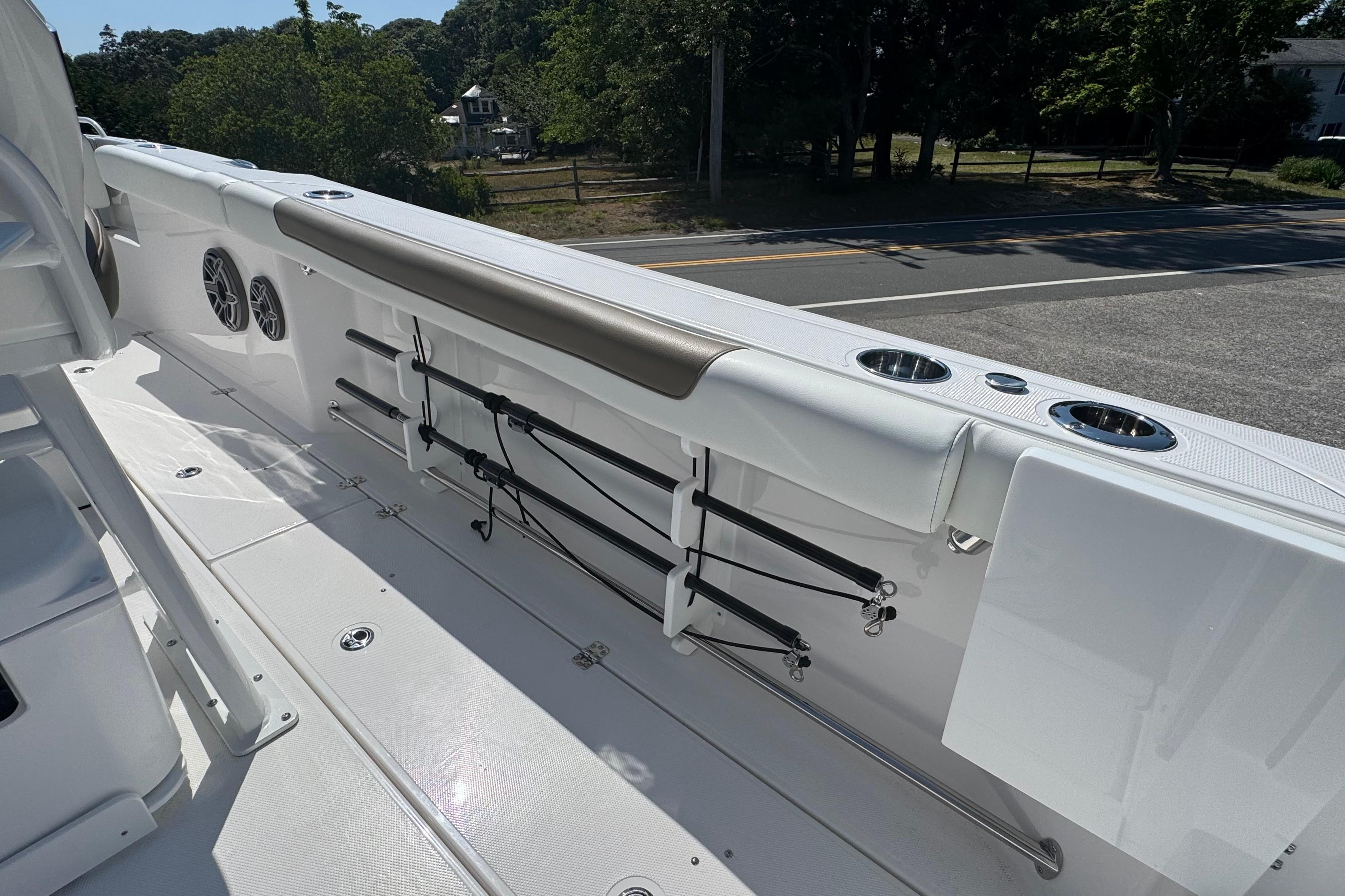 Edgewater 250CC 2026 boat interior with rod holders and cup holders, parked near a road.