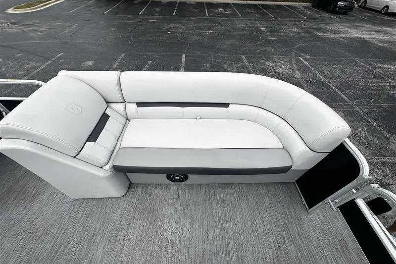 2023 Godfrey 2286 boat interior with white cushioned seating in a parking lot.
