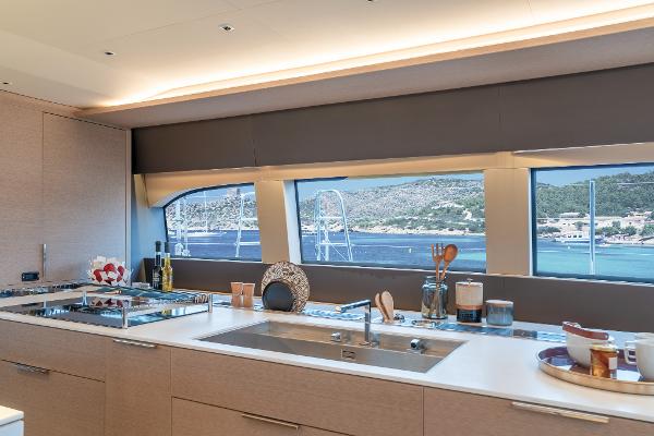 Modern kitchen interior on 2025 Lagoon SIXTY 5 yacht with ocean view.