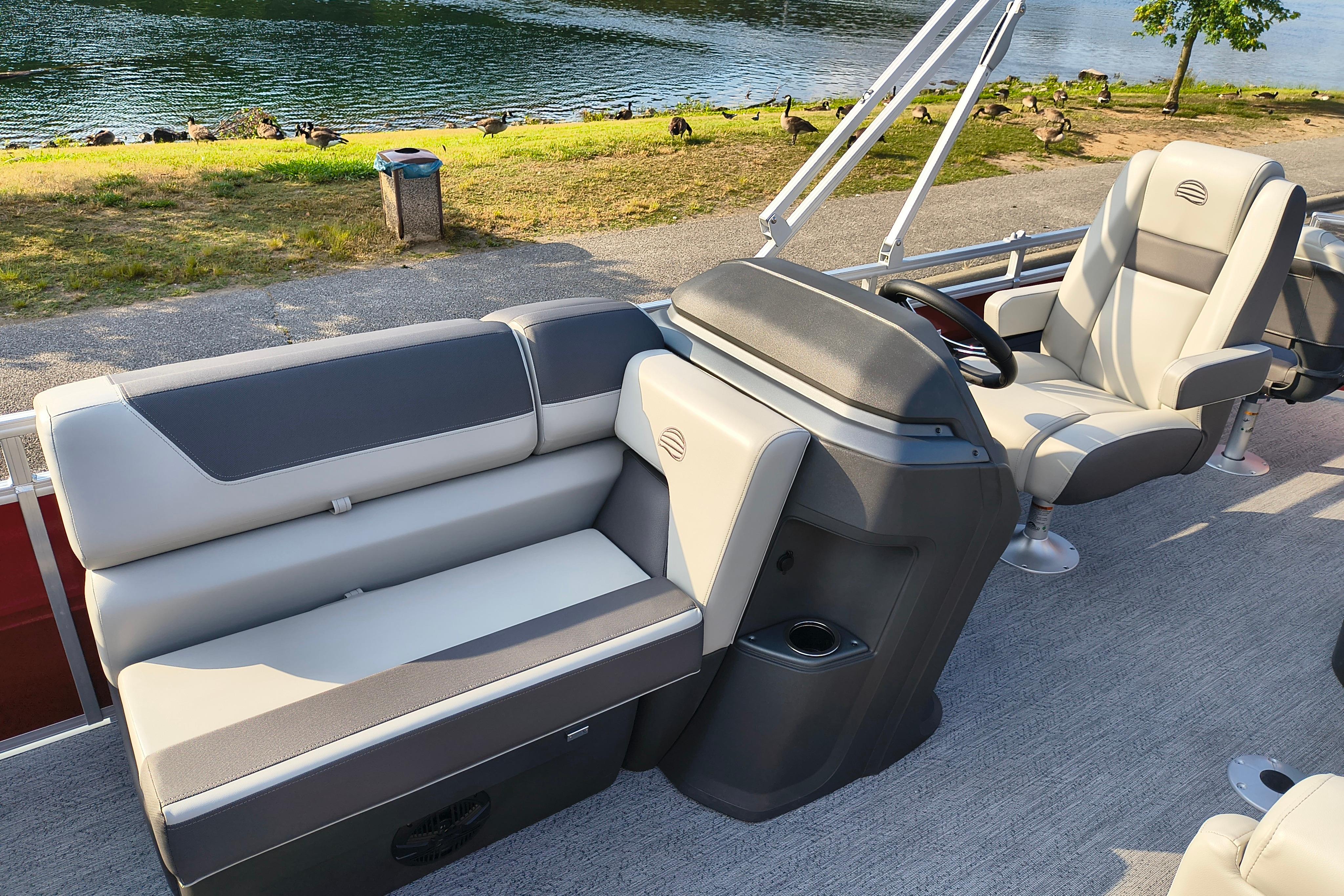 2026 Sun Tracker Fishin' Barge 22 DLX interior with plush seating by a serene lake.