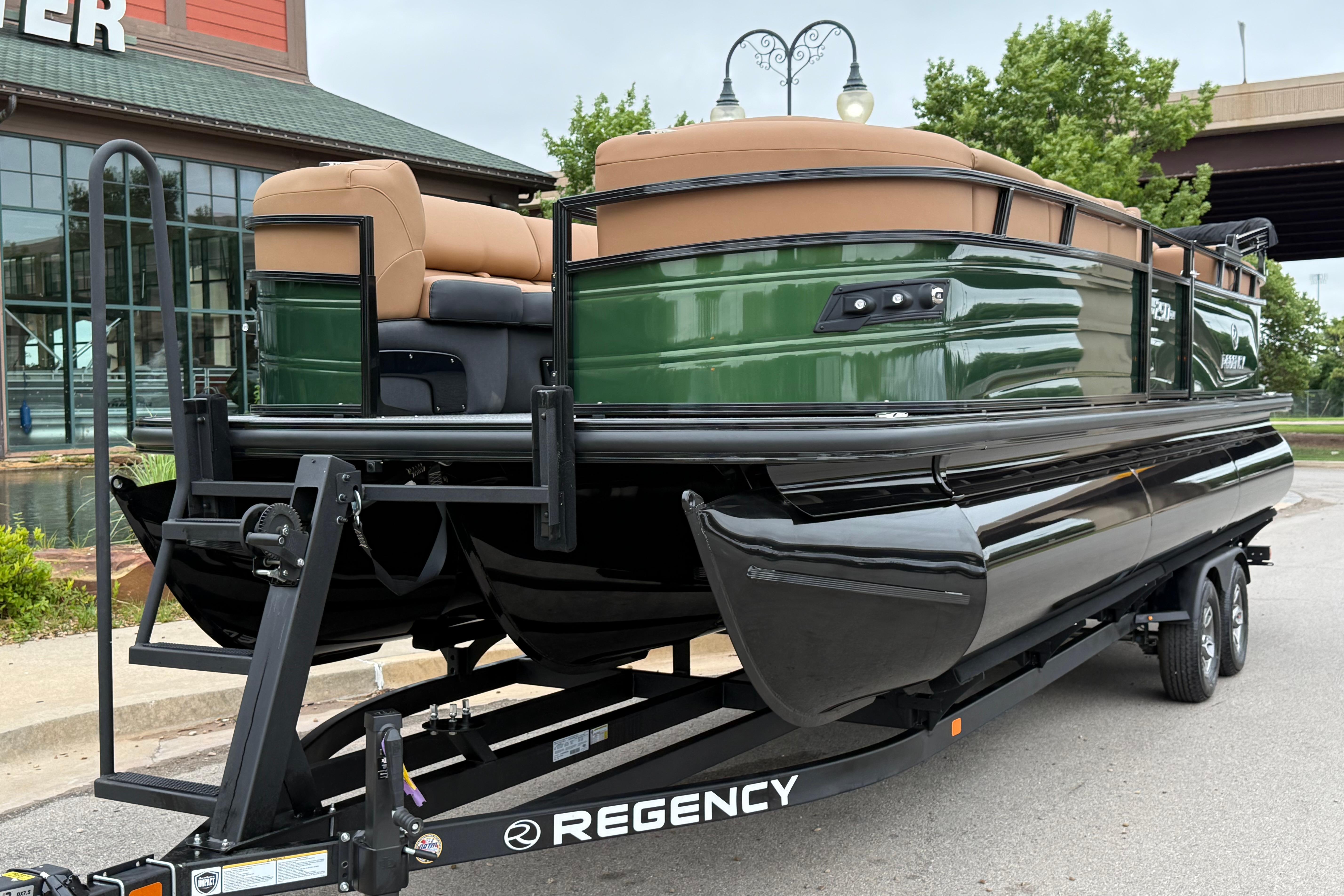 2026 Regency 250 DL pontoon boat on trailer, green and black design, parked outdoors.