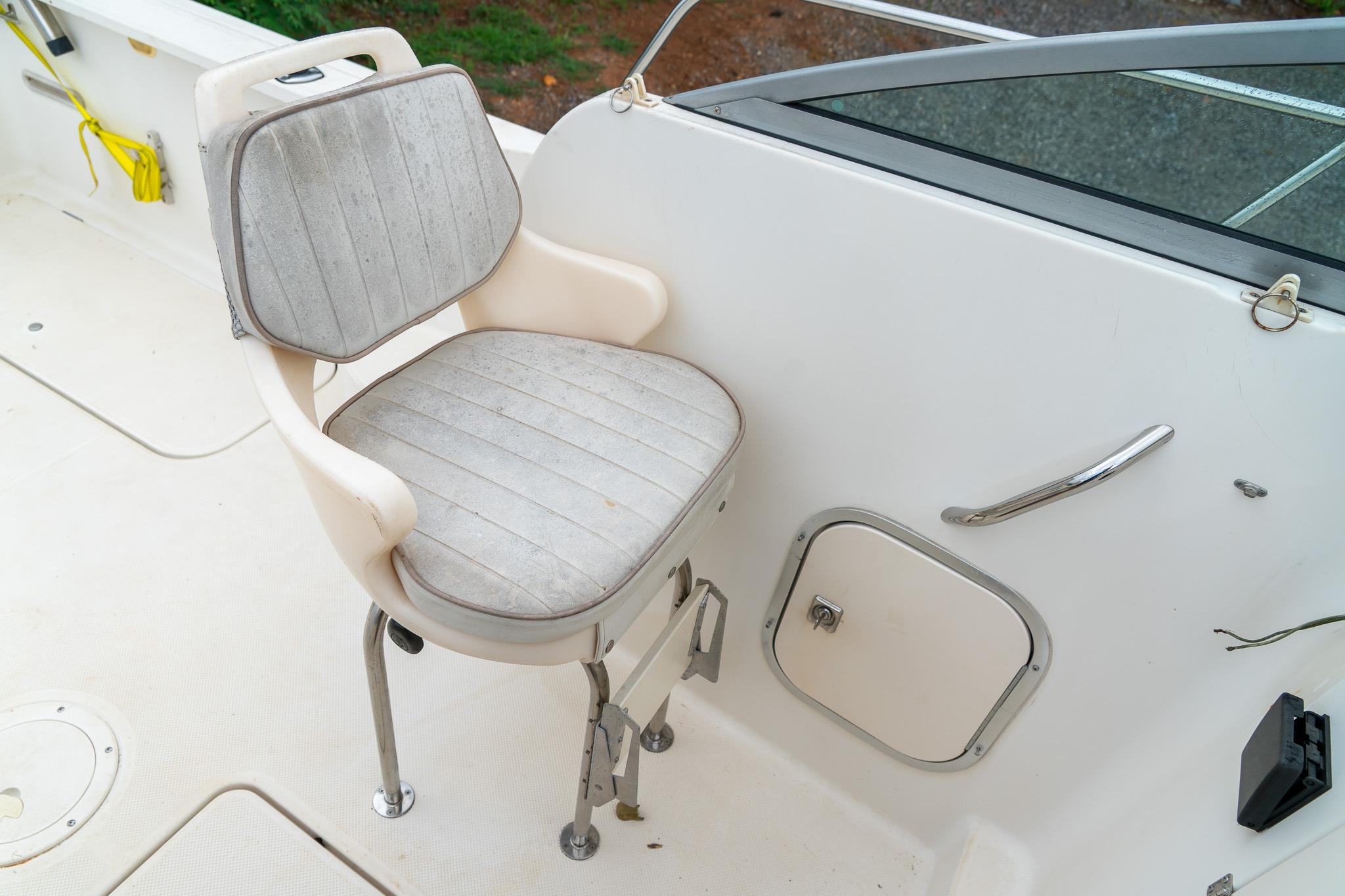 Captain's chair on 2002 Bayliner 2302 Trophy Walkaround boat deck, near storage compartment.