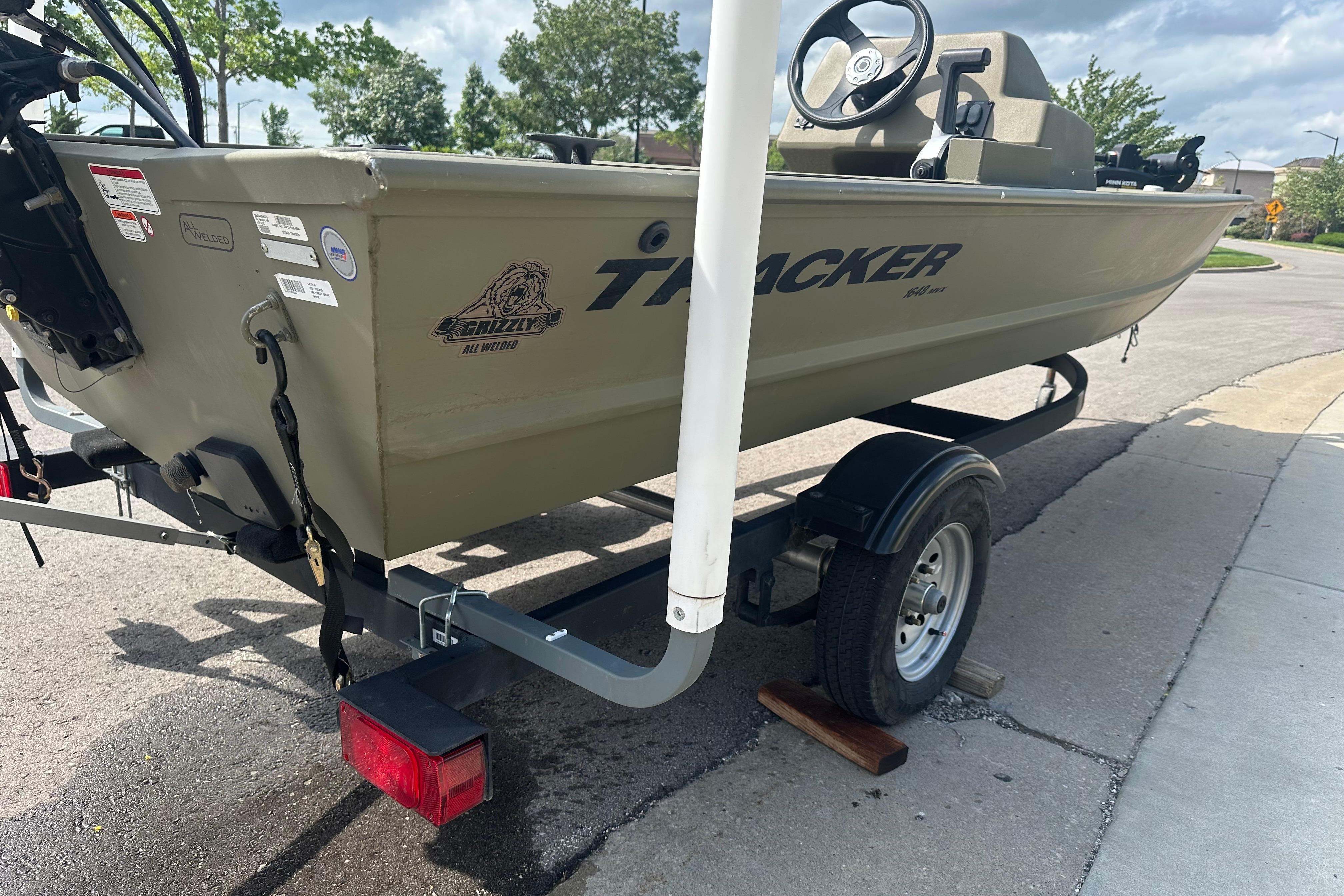 2024 Tracker Grizzly 1648 SC boat on trailer, parked on a street.