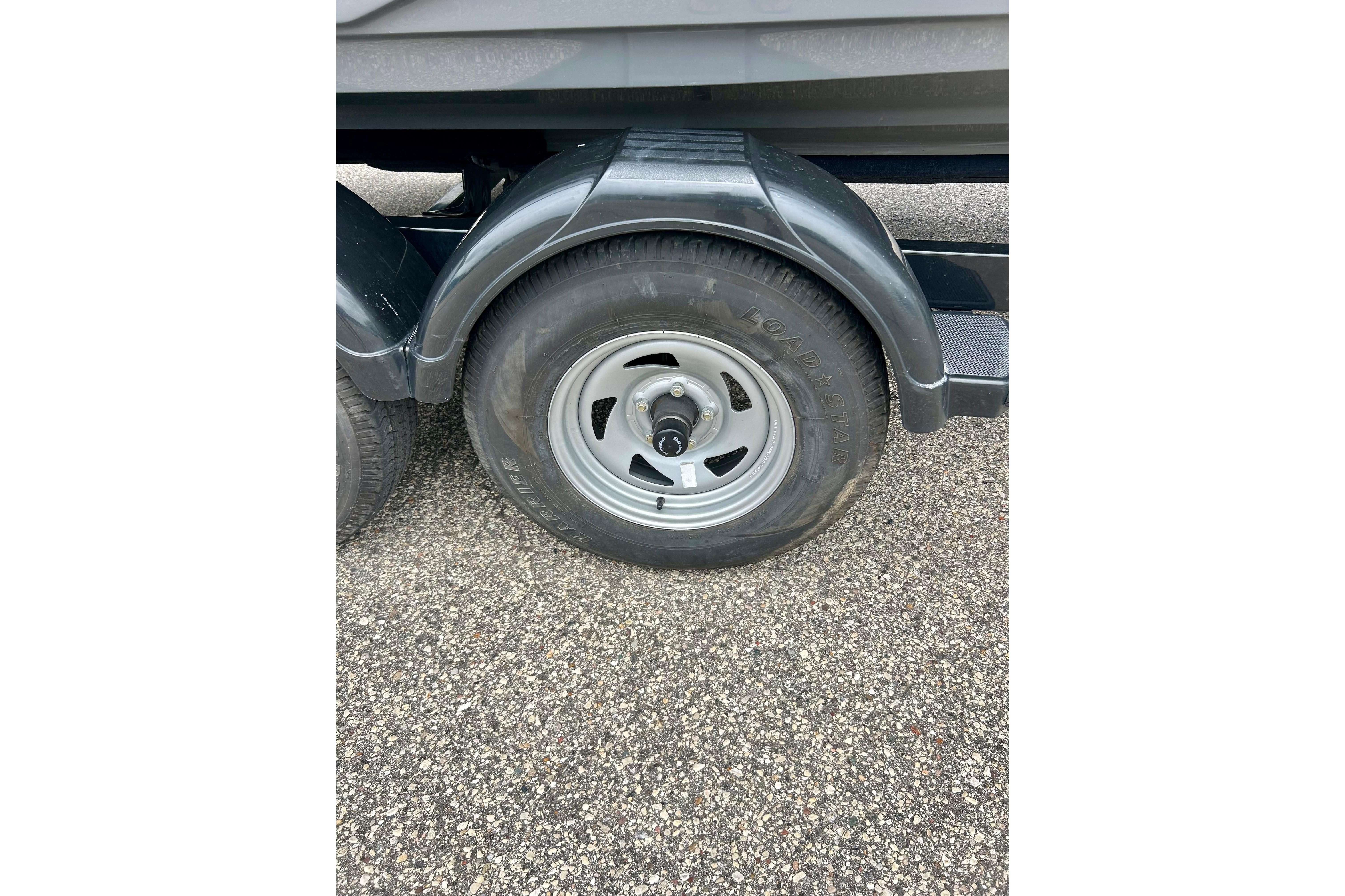 Trailer wheel of a 2015 Yamaha Boats AR210 on asphalt surface.
