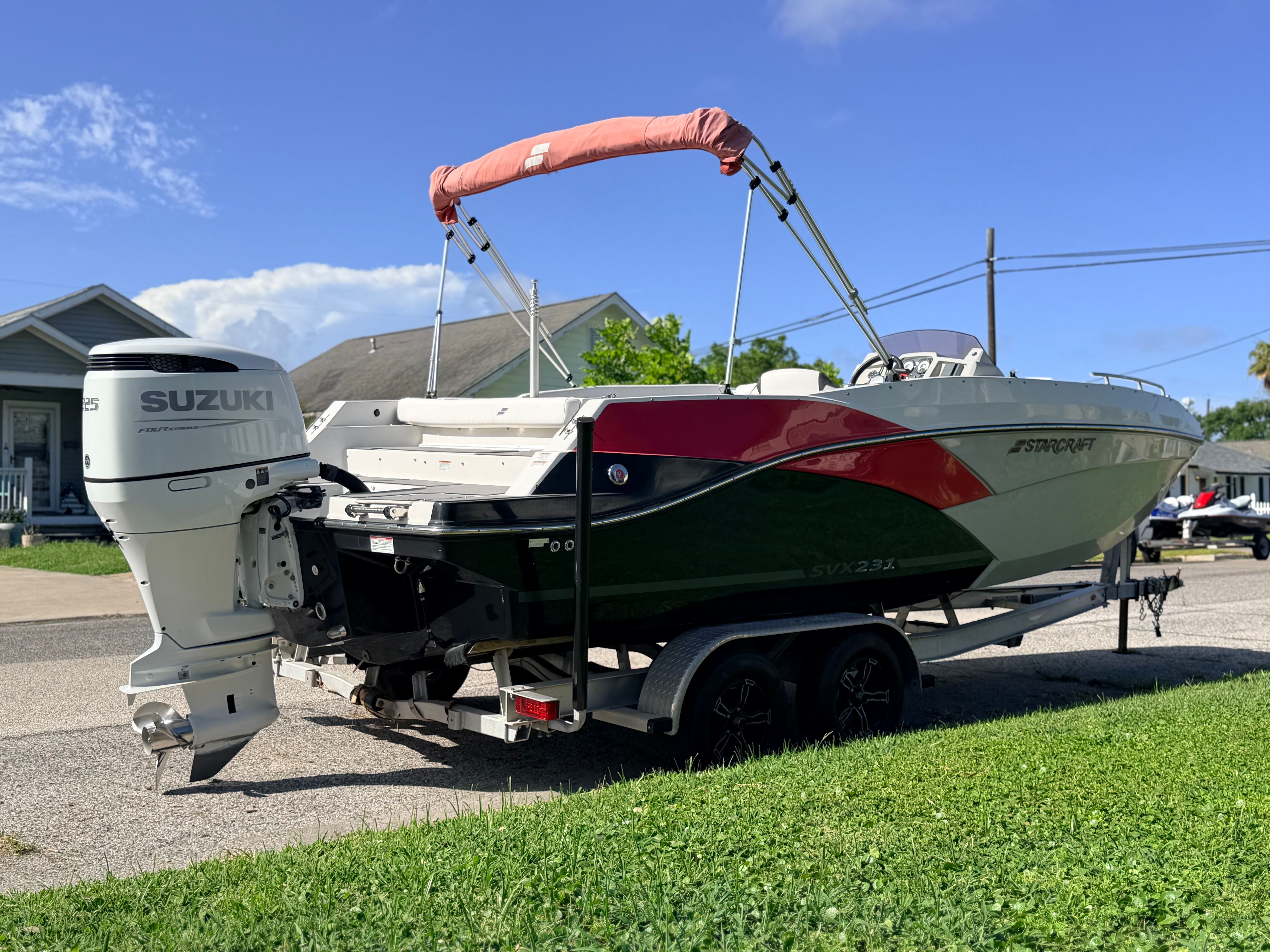 A 2022 Starcraft SVX 231 boat is on a trailer in a residential area.