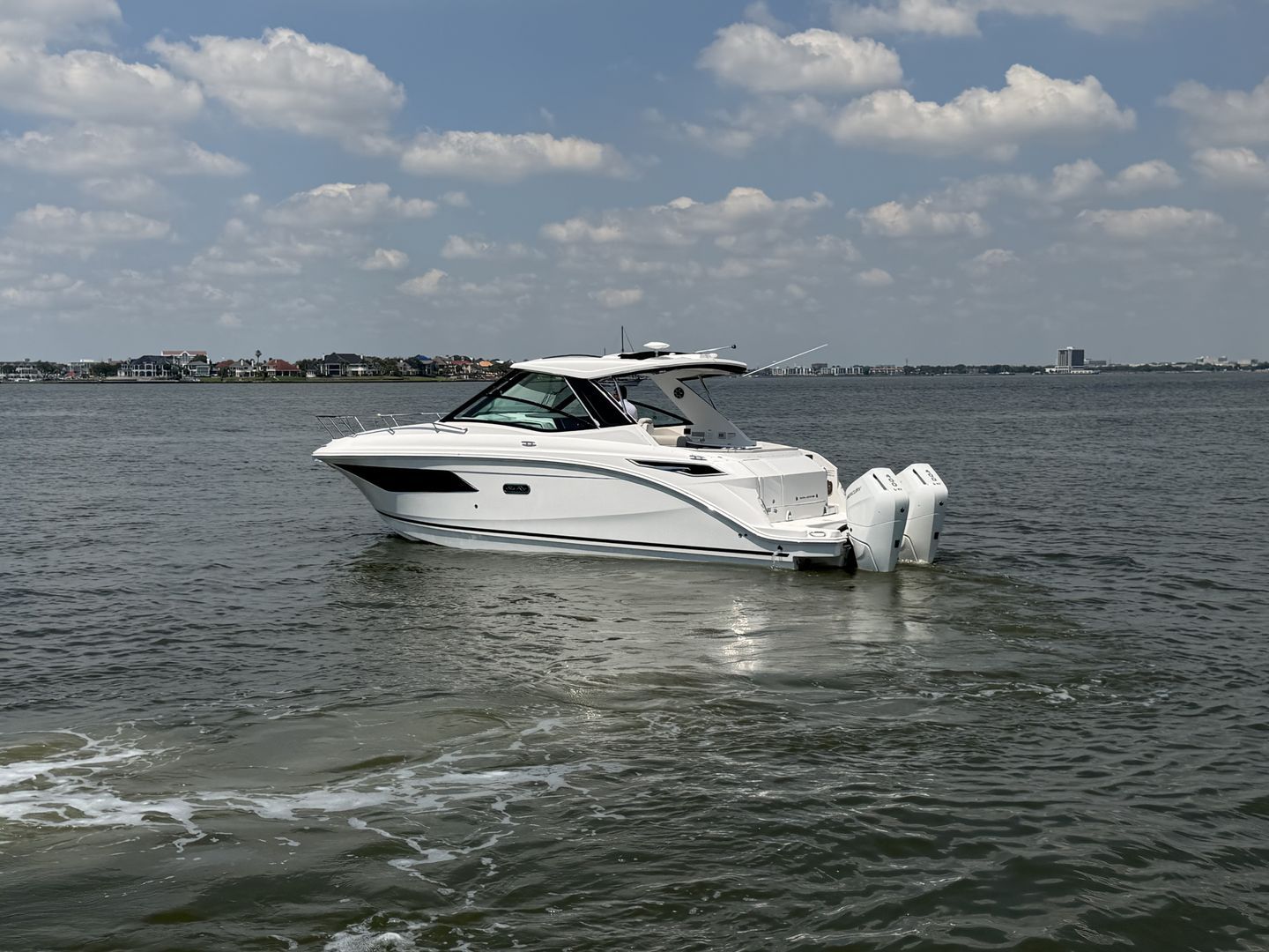 2026 Sea Ray Sundancer 320 Outboard on calm waters under cloudy sky.