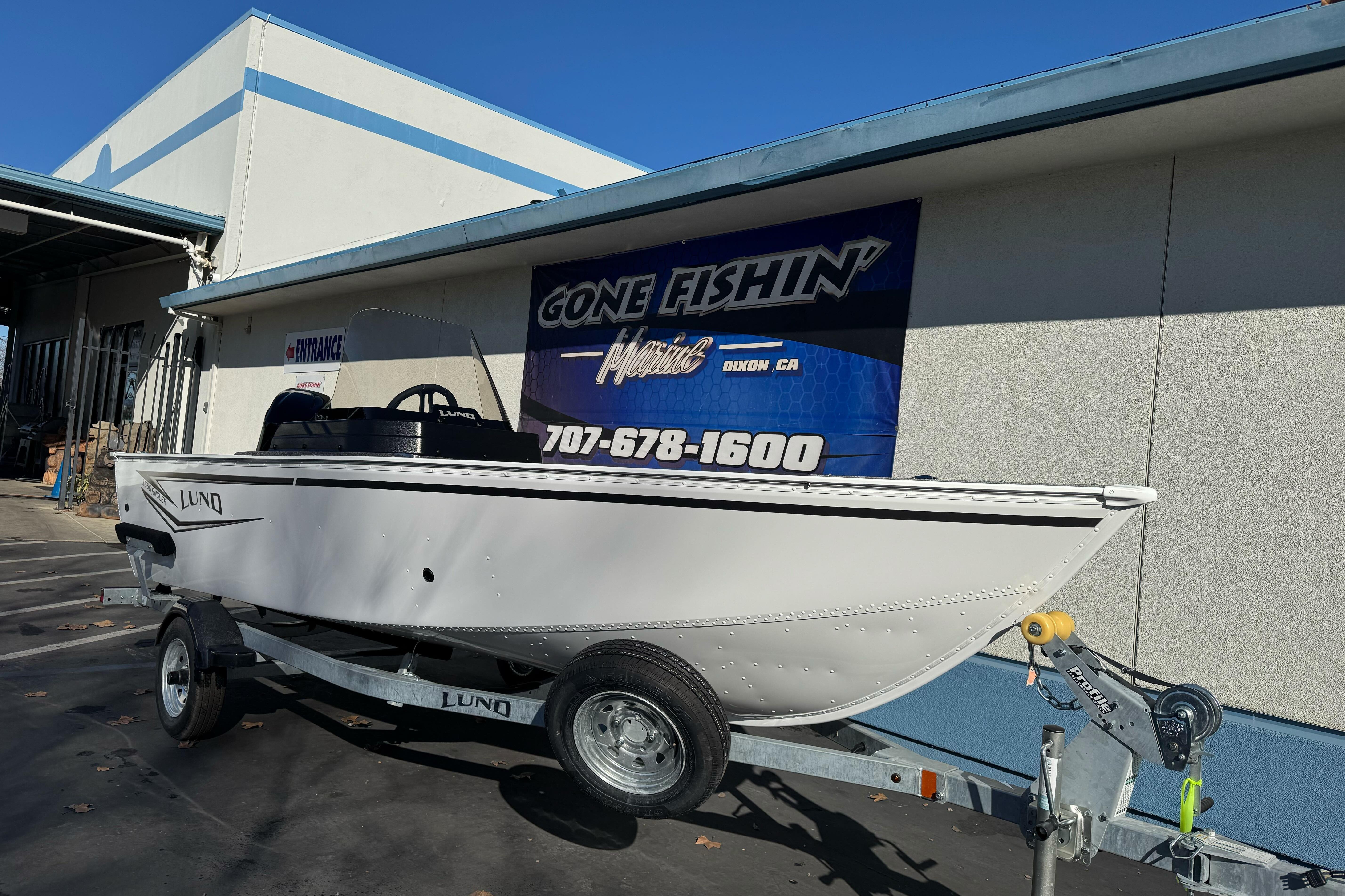 2026 Lund 1650 Angler SS boat on trailer outside dealership, "Gone Fishin'" sign visible.