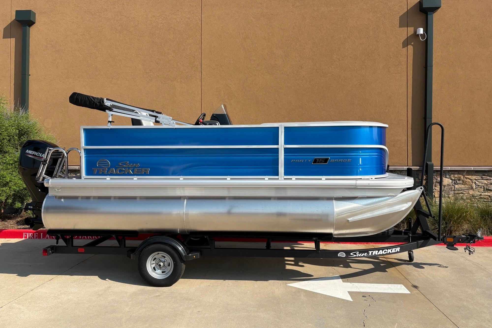 2026 Sun Tracker Party Barge 16 DLX pontoon boat on trailer, blue and silver design.