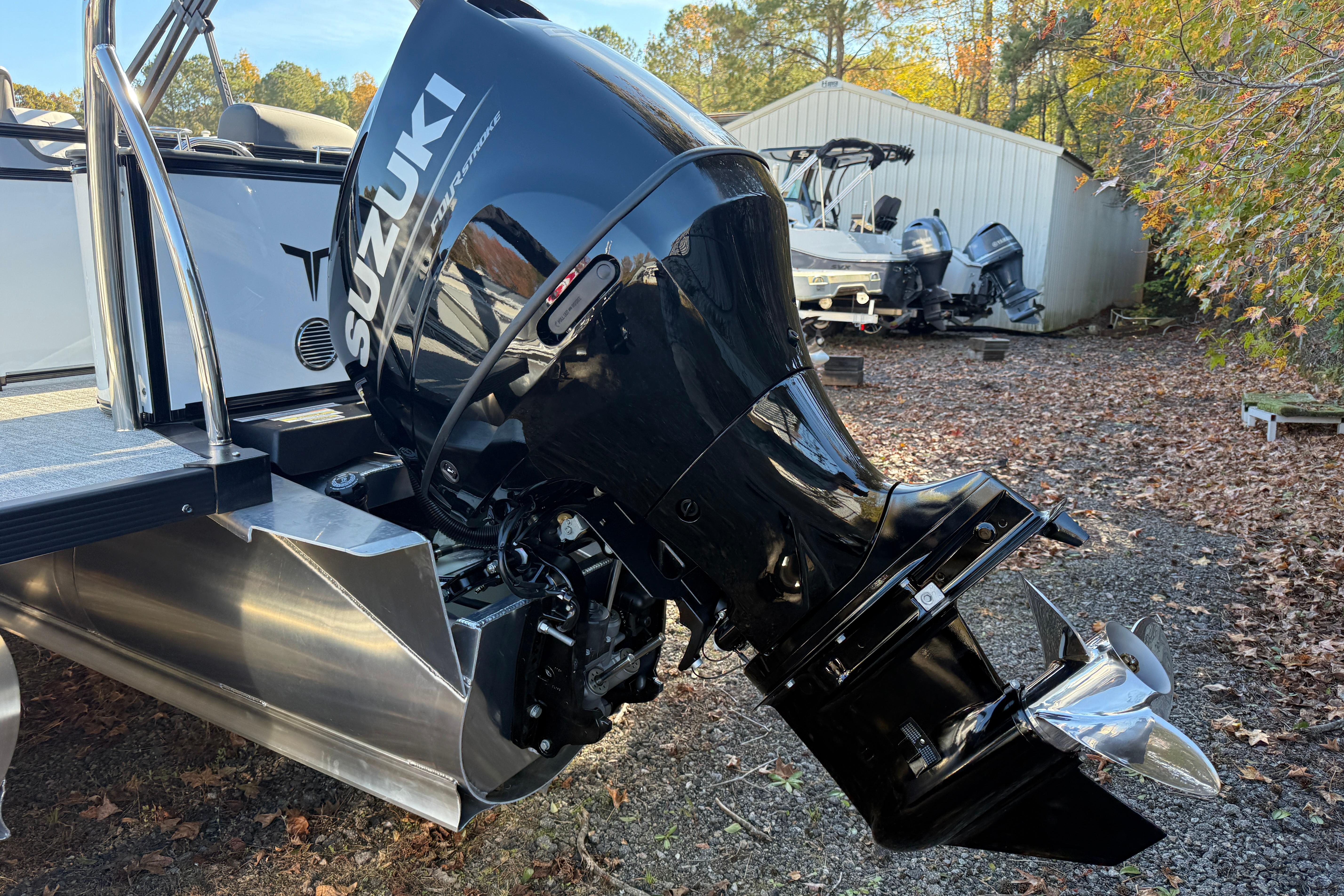 2026 Tahoe Pontoon LTZ Quad Lounger with Suzuki outboard motor in a wooded area.