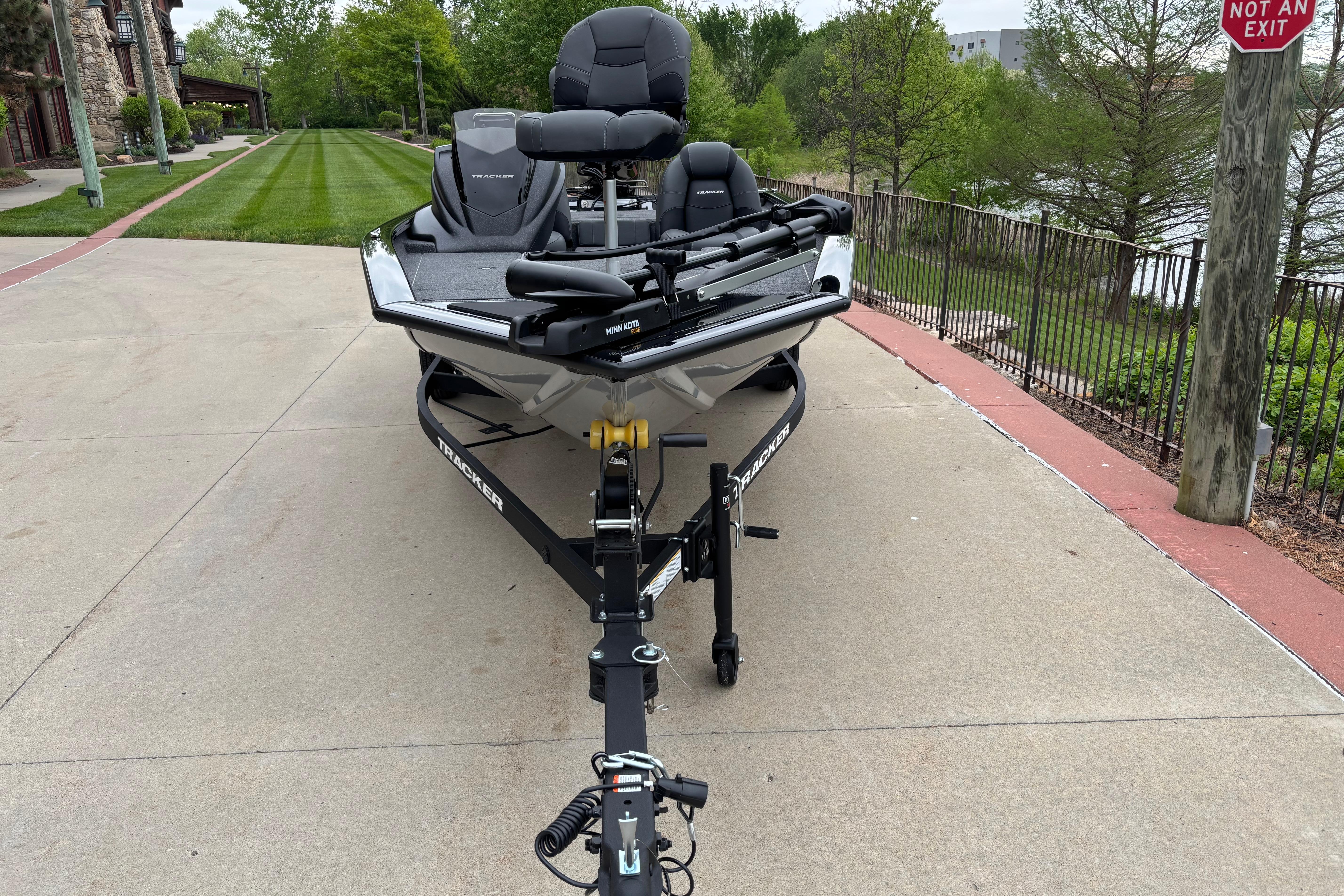 2026 Tracker Pro Team 175 boat on trailer, parked on a paved path near greenery.