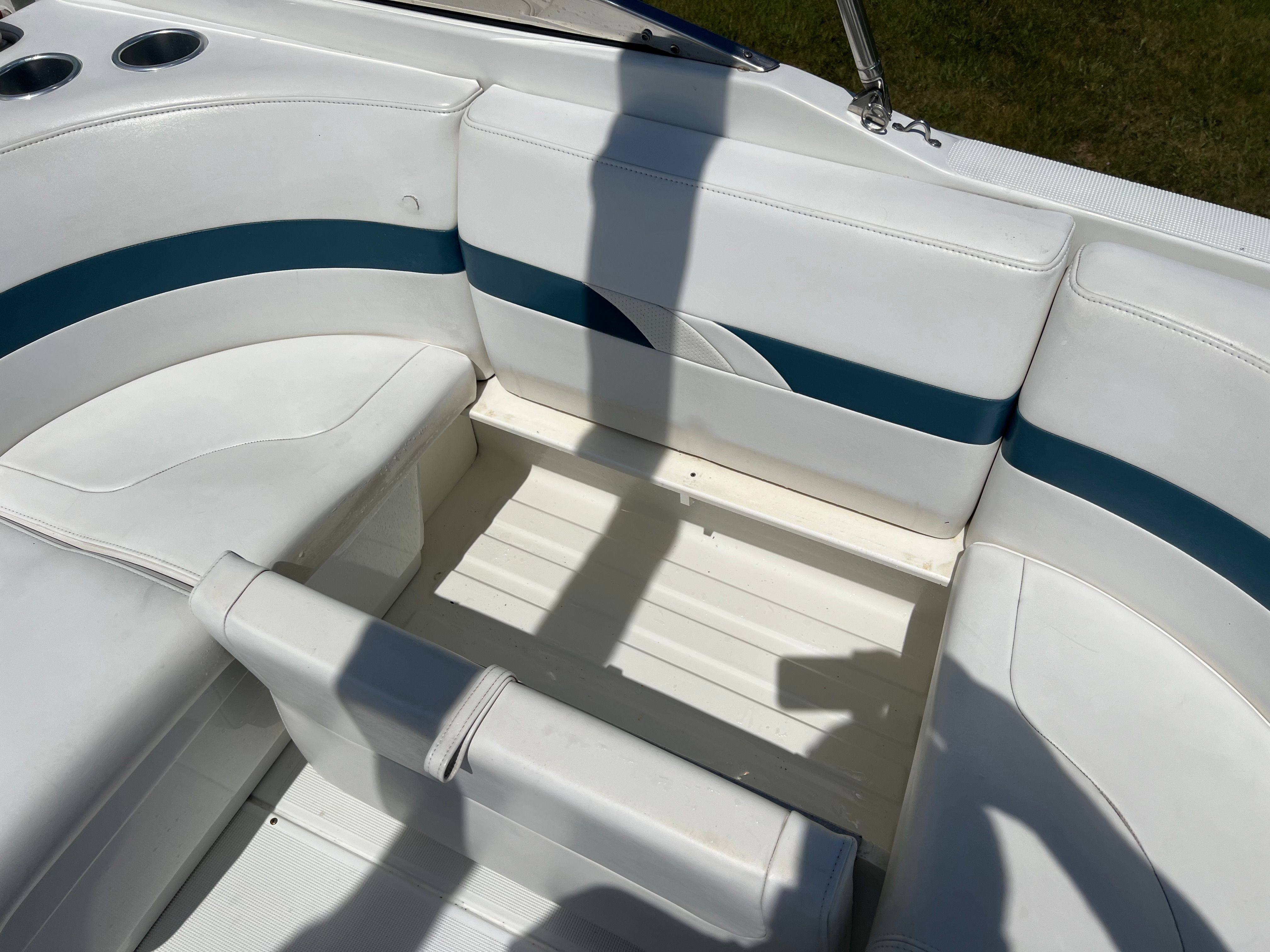The seating area of a boat with white and blue upholstery. Cup holders are visible.
