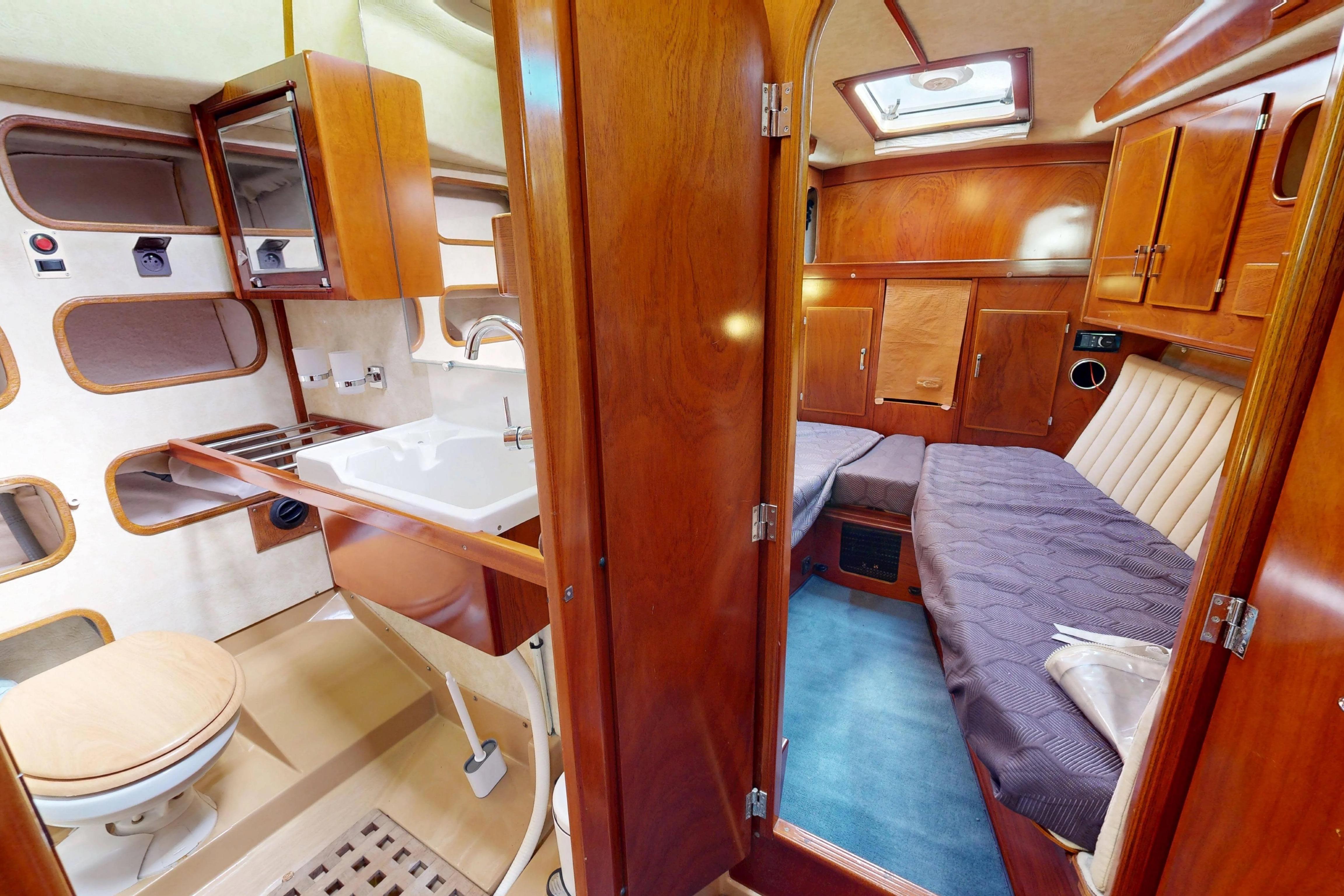 Interior of 1999 Amel Super Maramu 2000 yacht, featuring wood finishes and compact living space.