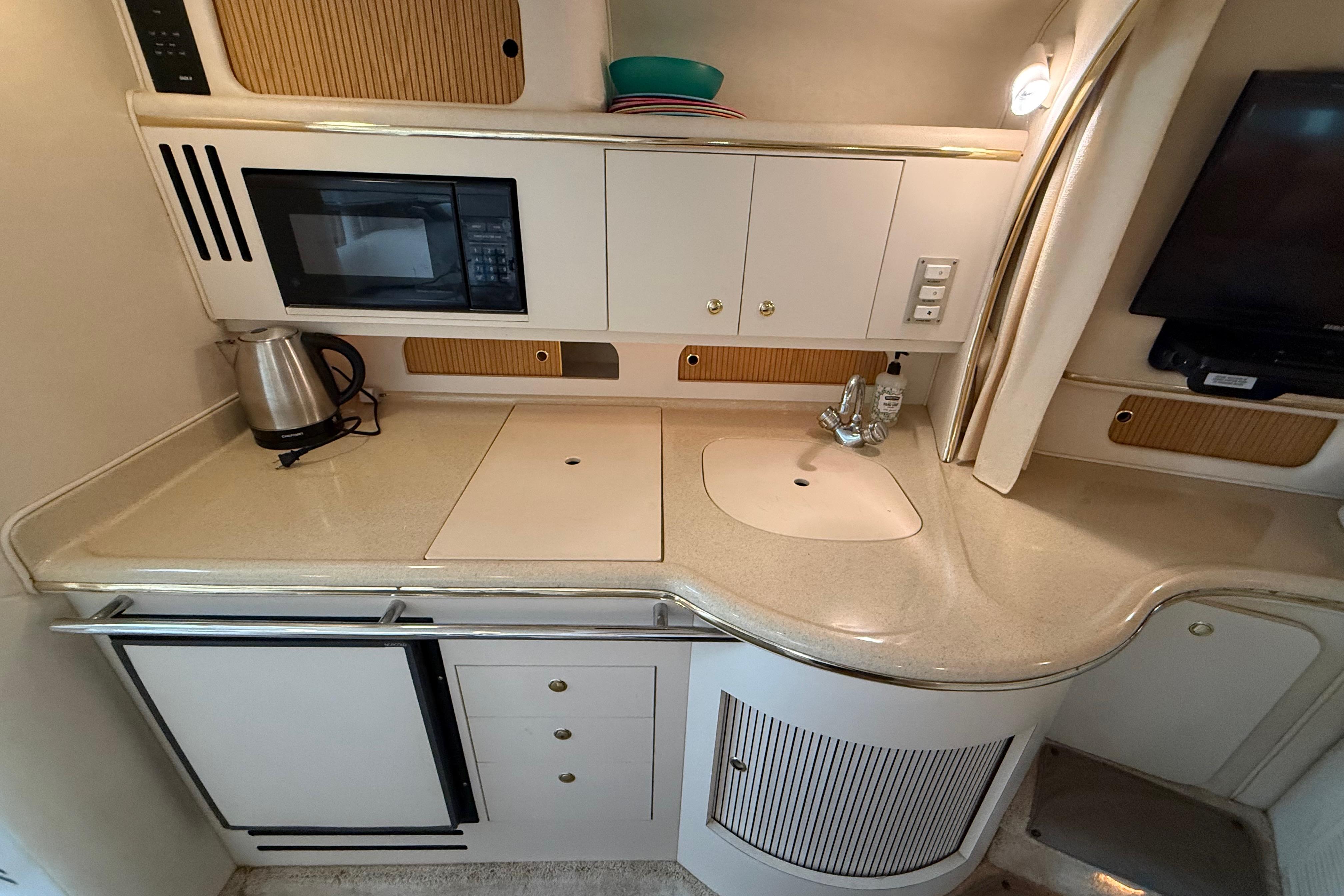 1999 Sea Ray Sundancer 310 yacht kitchen with microwave, sink, and kettle.