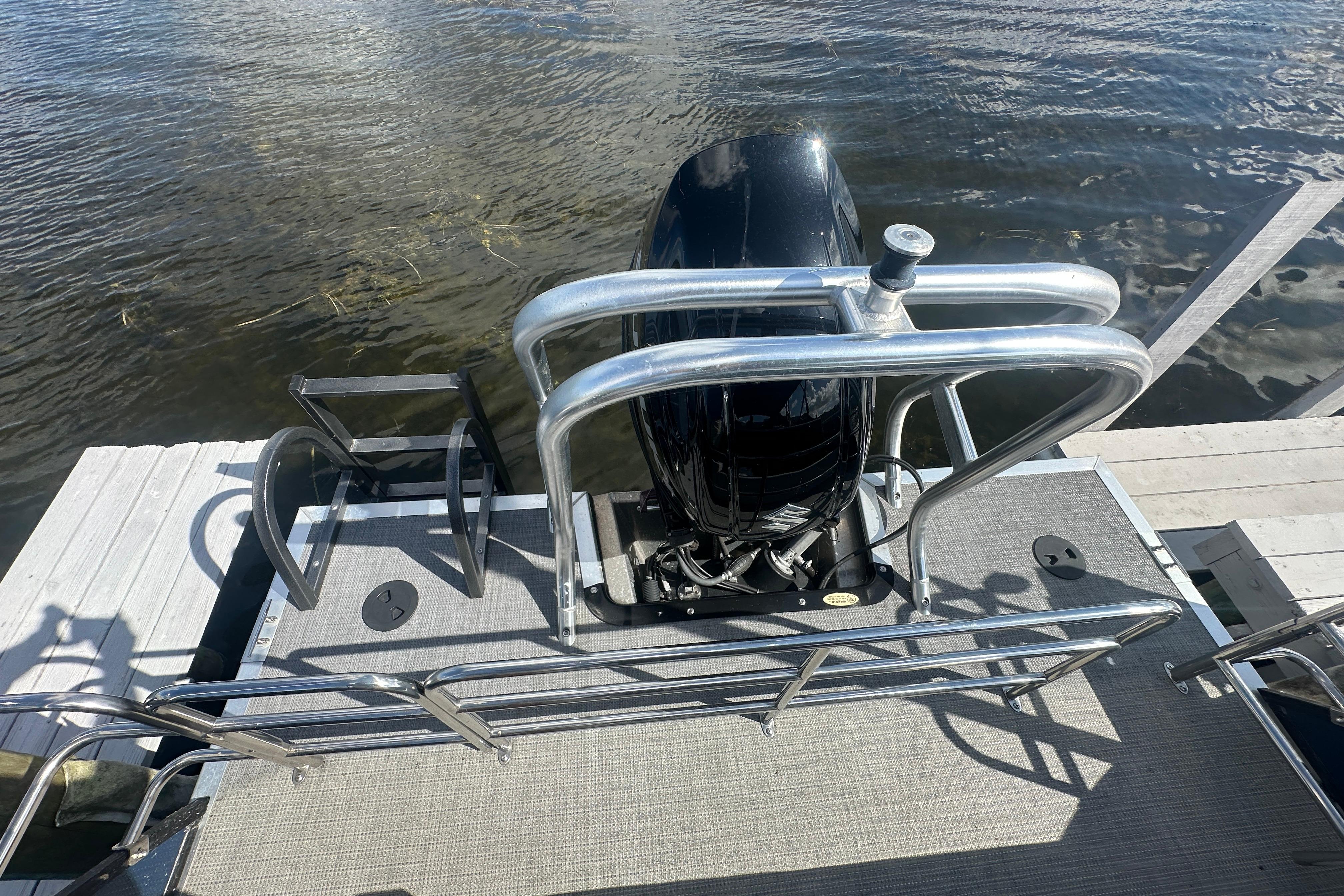2023 Bentley Pontoons Legacy 243 Swingback with outboard motor, docked on calm water.