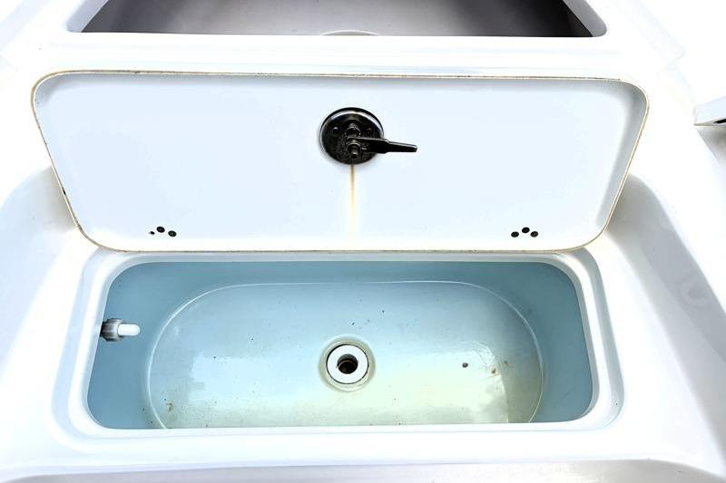 Livewell compartment on a 2025 Key West 210 Bay Reef boat, featuring a drain and latch.