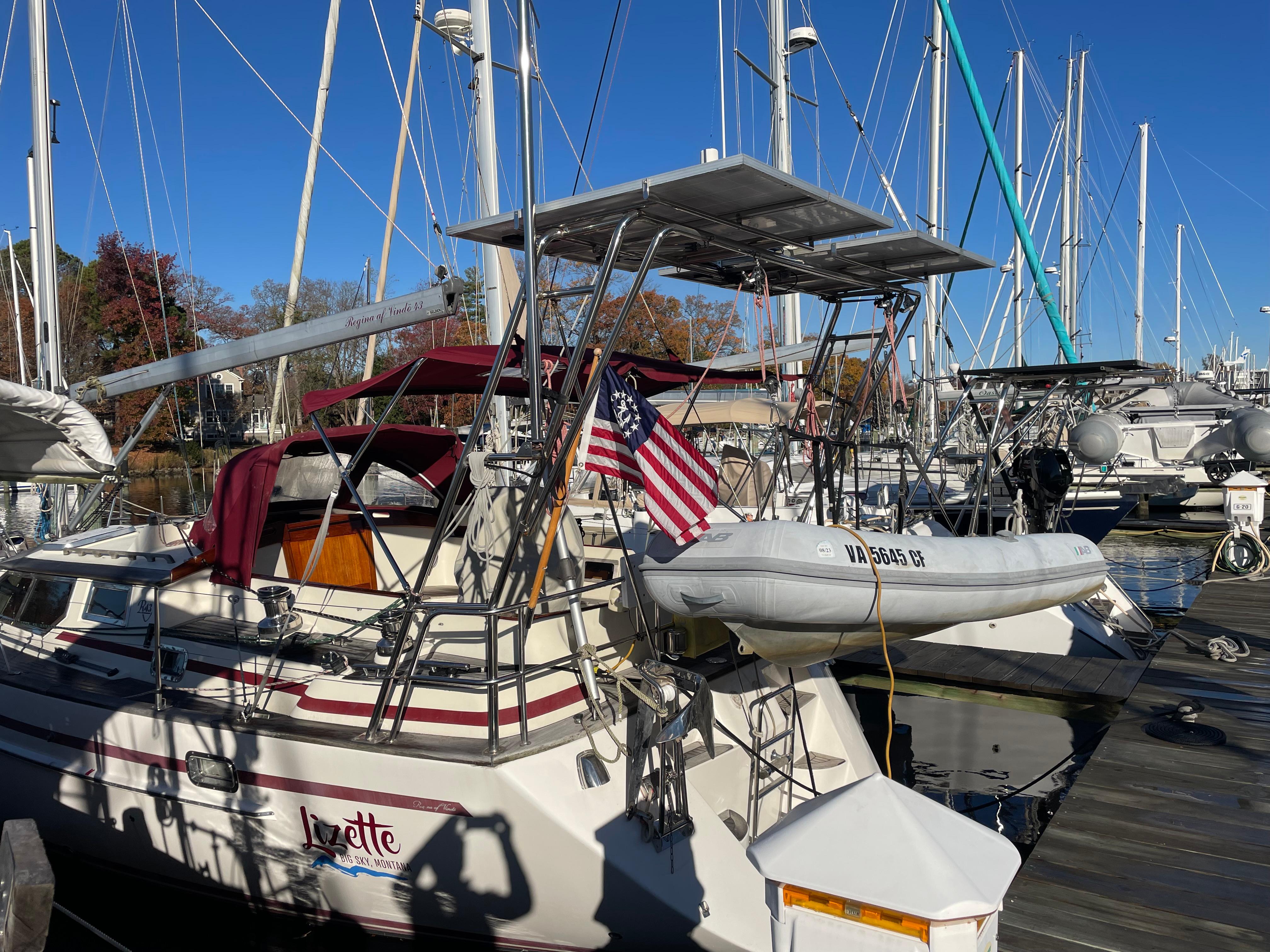 Sailboat docked at marina, Regina 43 model, 2000, with American flag and dinghy.