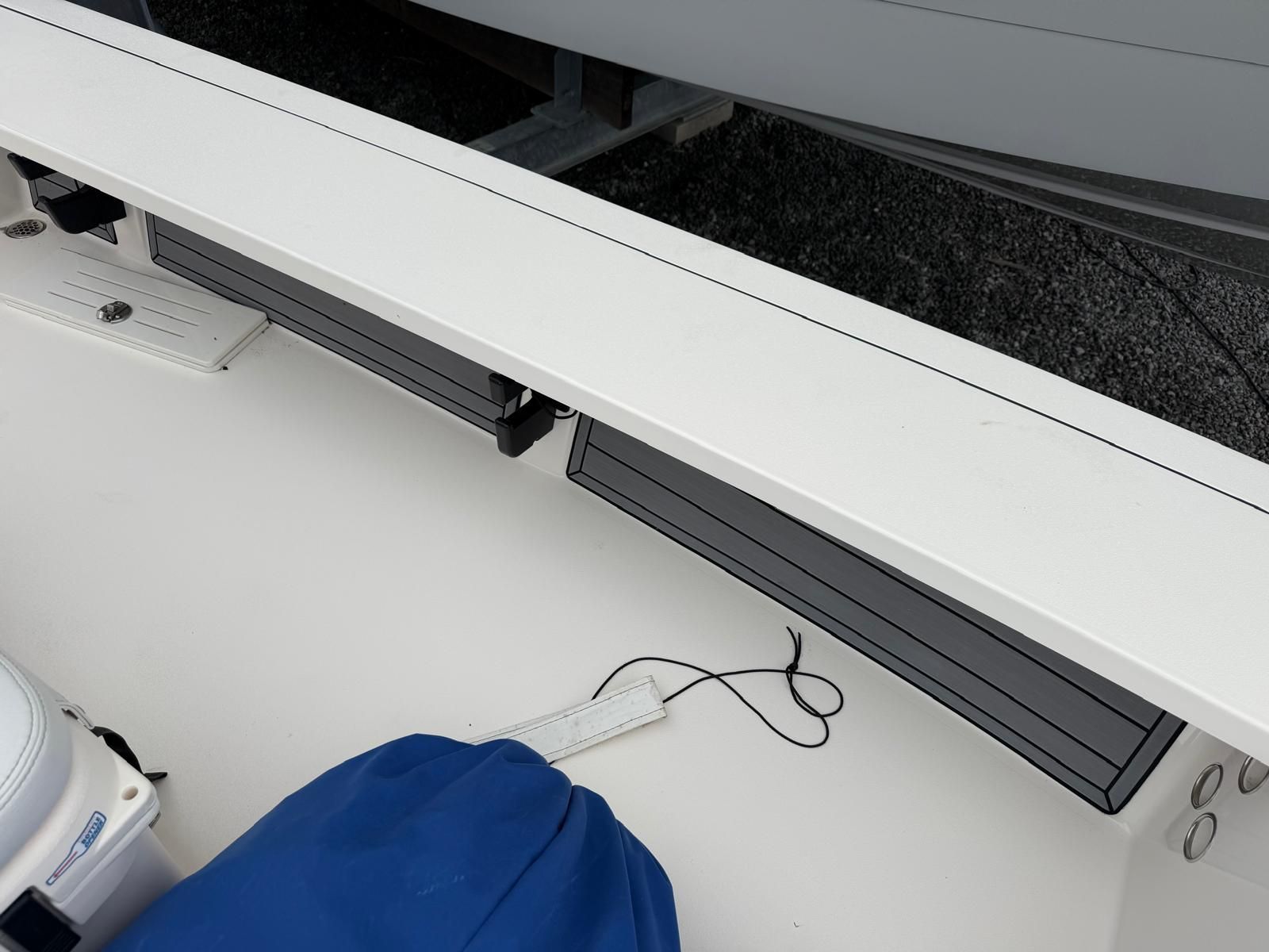The image shows a boat deck with storage compartments and a blue cover.