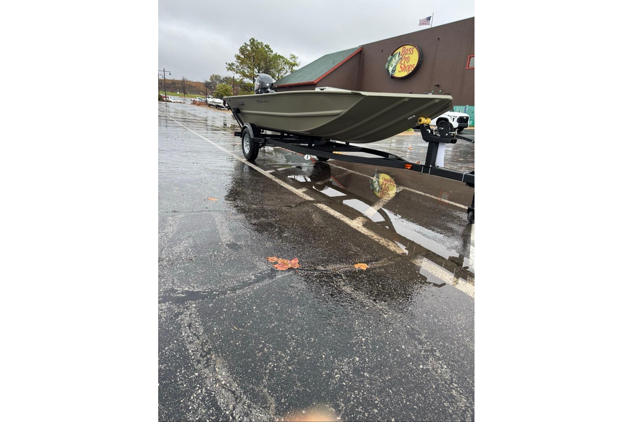 2026 Tracker Grizzly 1654 T Sportsman boat on trailer in rainy parking lot.