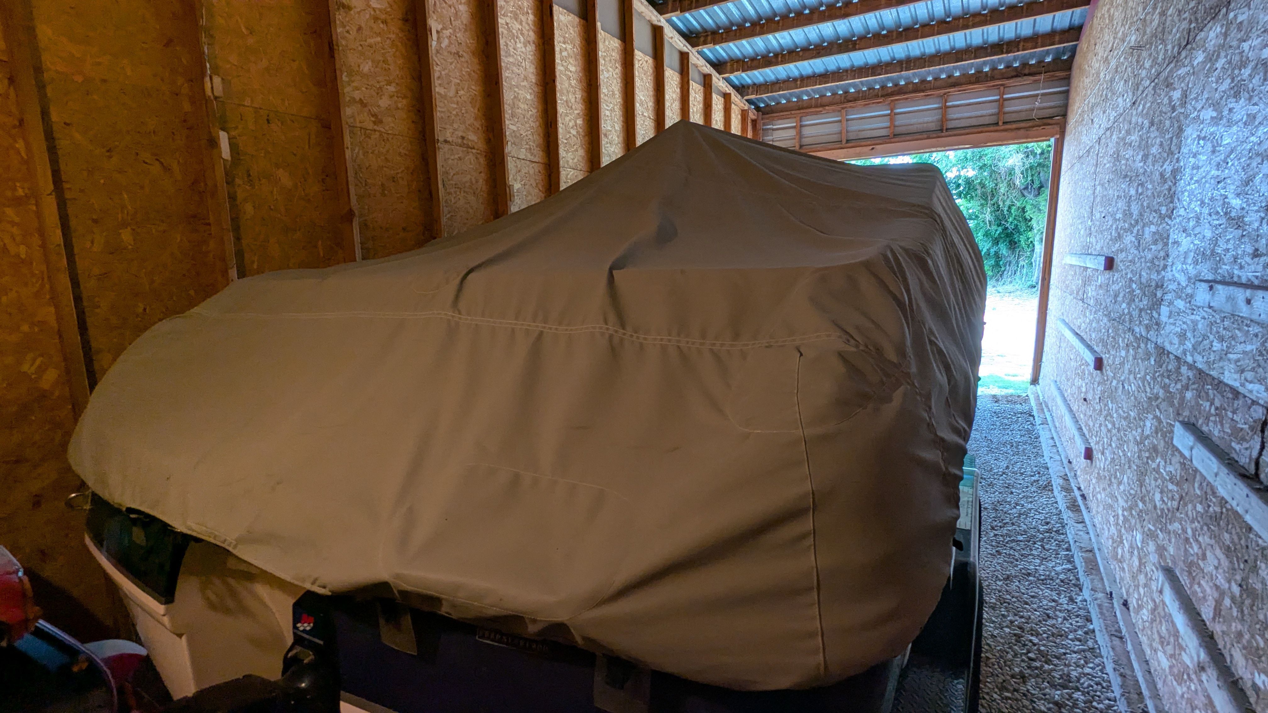 A 2000 Chaparral 240 SSi boat is covered in a barn.