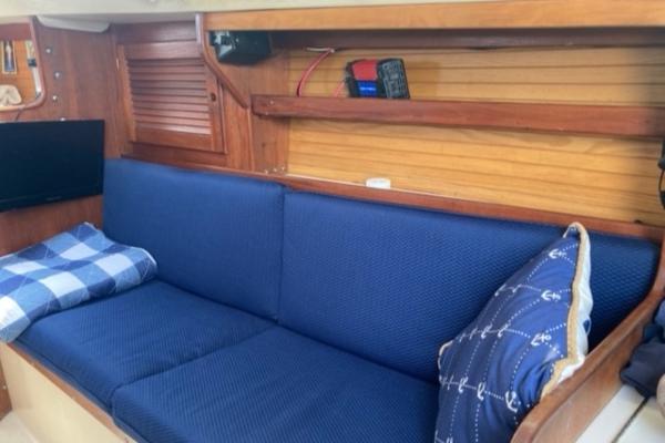 Interior of 1989 Catalina 30 sailboat with blue cushioned seating and nautical-themed pillows.