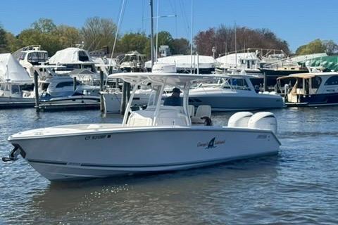 2023 Jupiter 30 boat cruising in a marina with other vessels in the background.