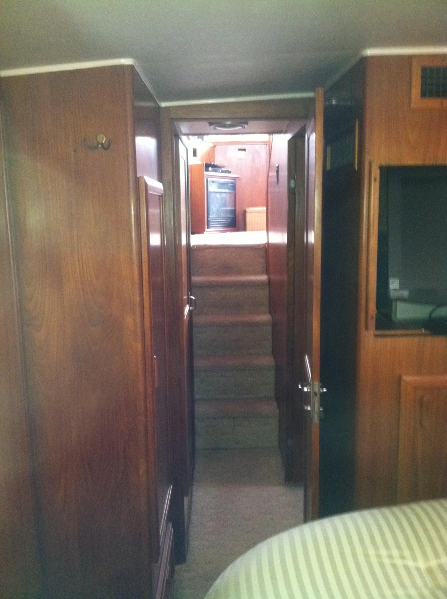 Interior hallway of 1989 Californian 48 Motor Yacht with wooden paneling and stairs.