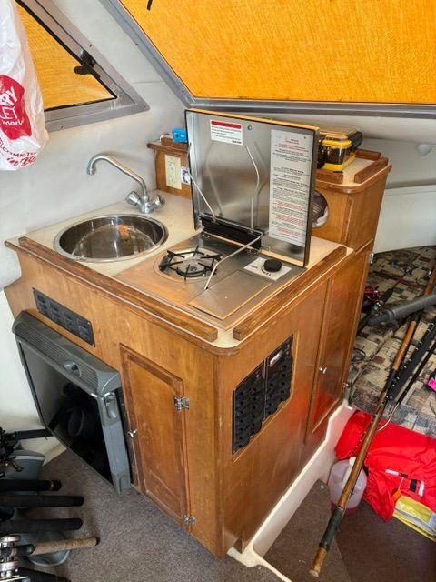 Small kitchen on a boat with sink, stove, and cabinets.