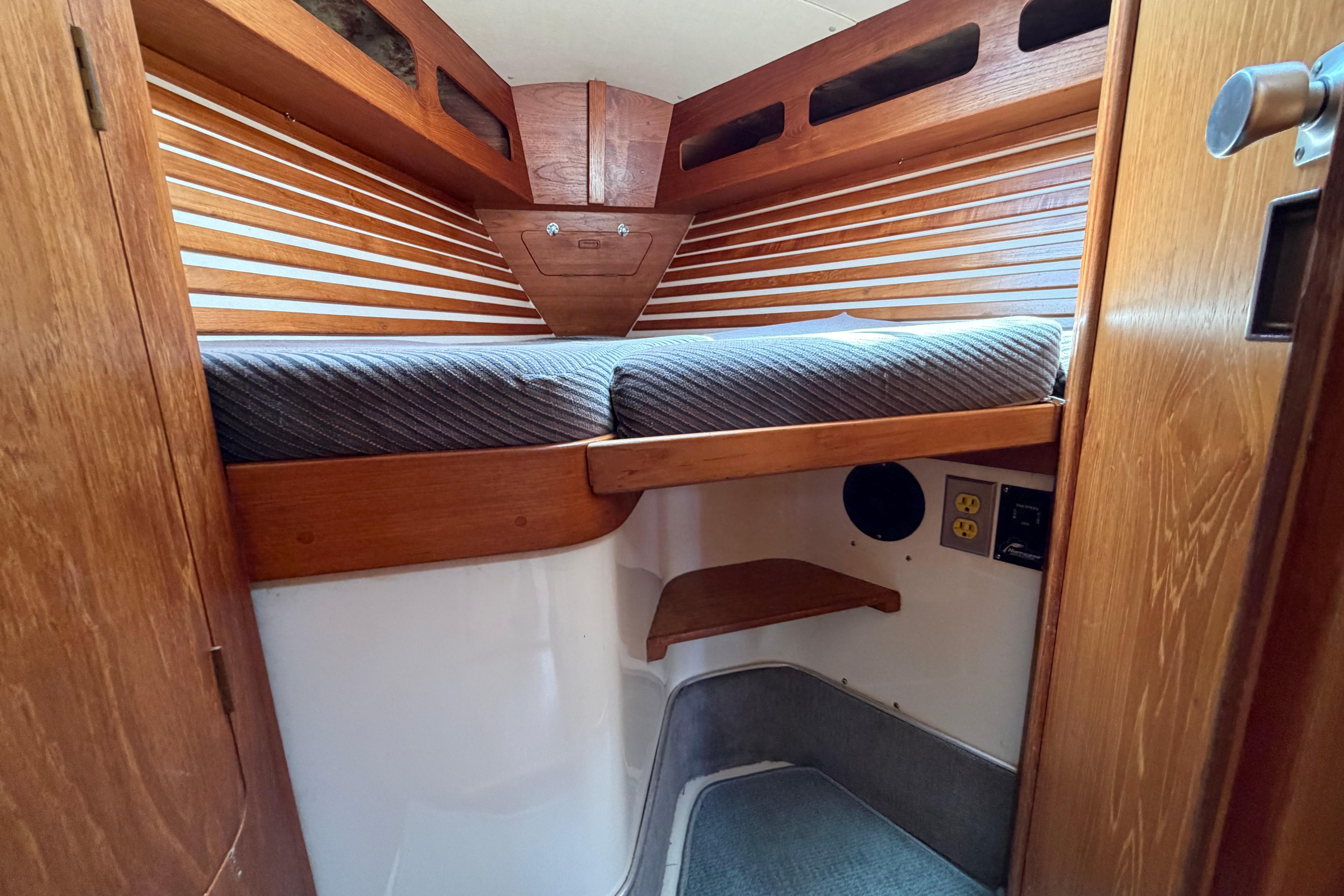 Cozy cabin interior of a 1987 Moody 376 sailboat with wooden accents and a cushioned berth.