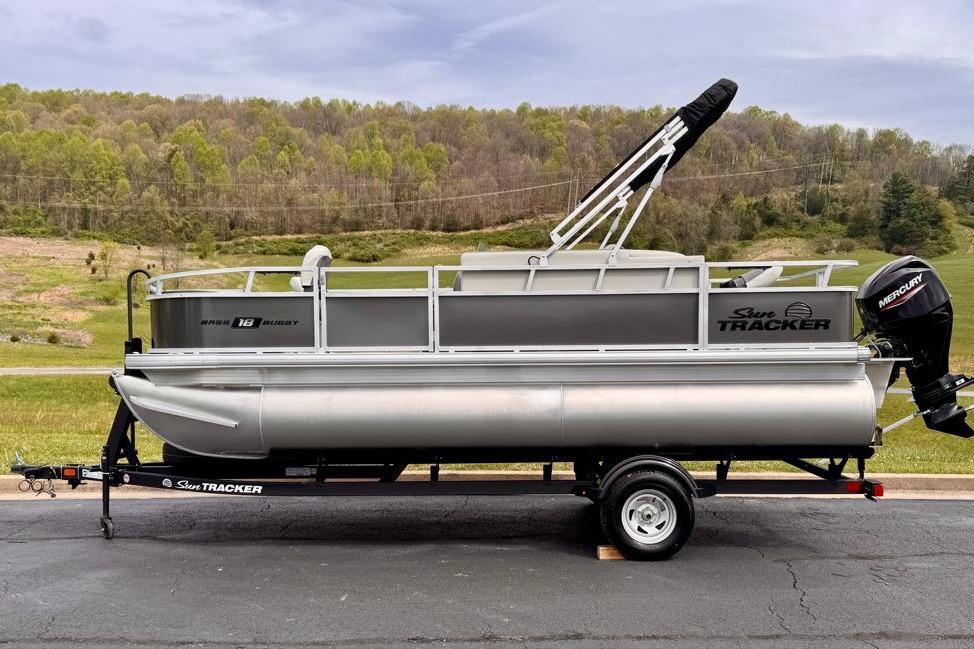 2026 Sun Tracker Bass Buggy 18 DLX pontoon boat on trailer, scenic background.
