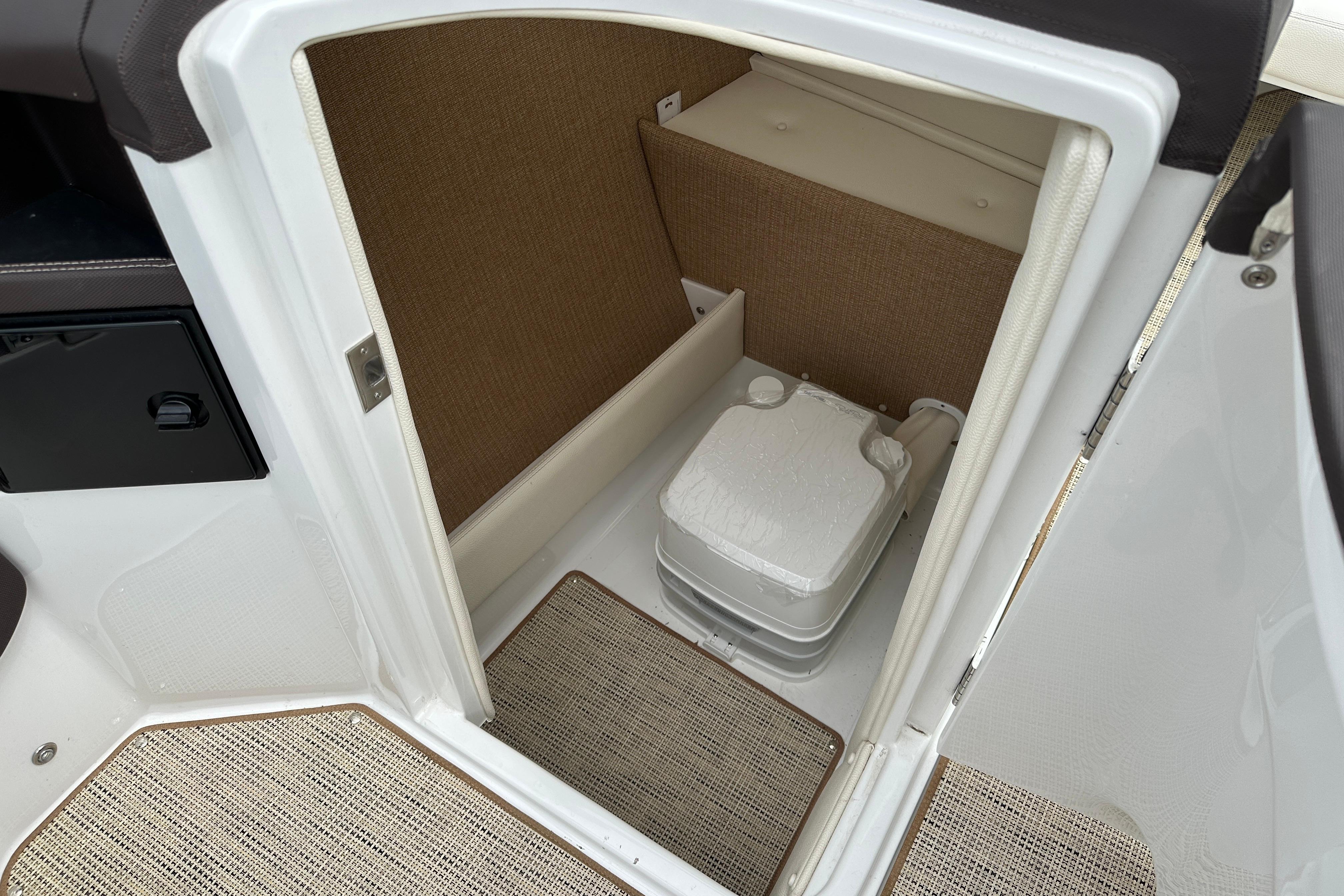 2019 Cobalt R5 boat interior with compact portable toilet and beige carpeting.