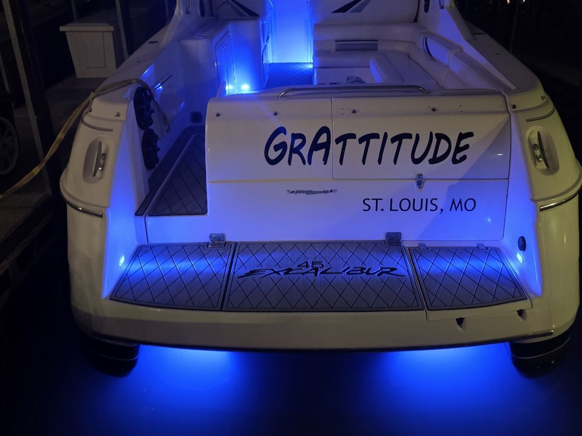 The image shows the stern of a boat with blue underwater lighting and the name "GRATTITUDE."
