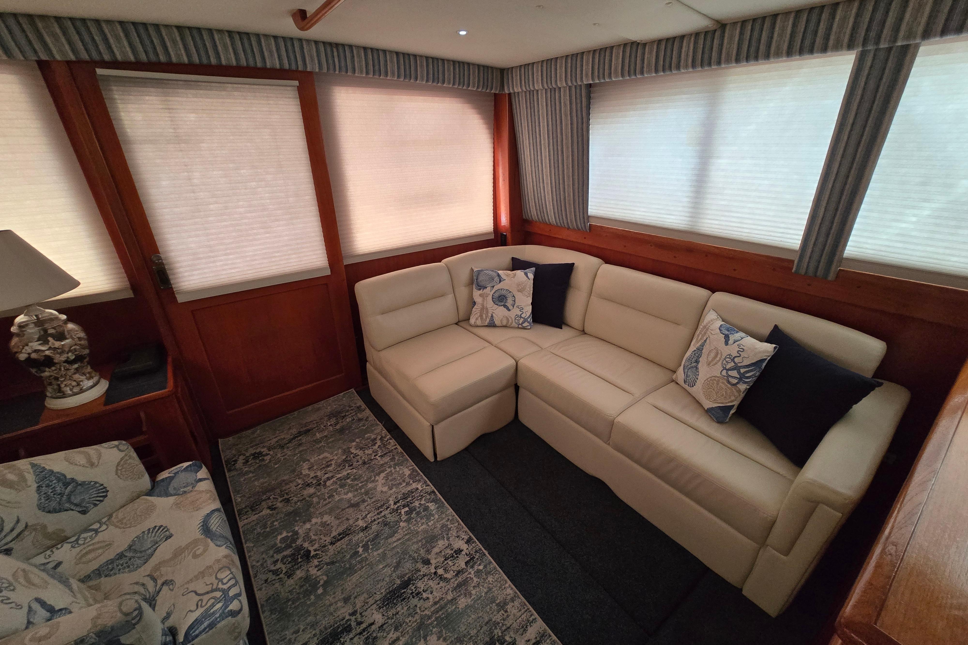Luxurious interior of 1988 Post 46 Convertible yacht with beige sectional sofa and decorative pillows.