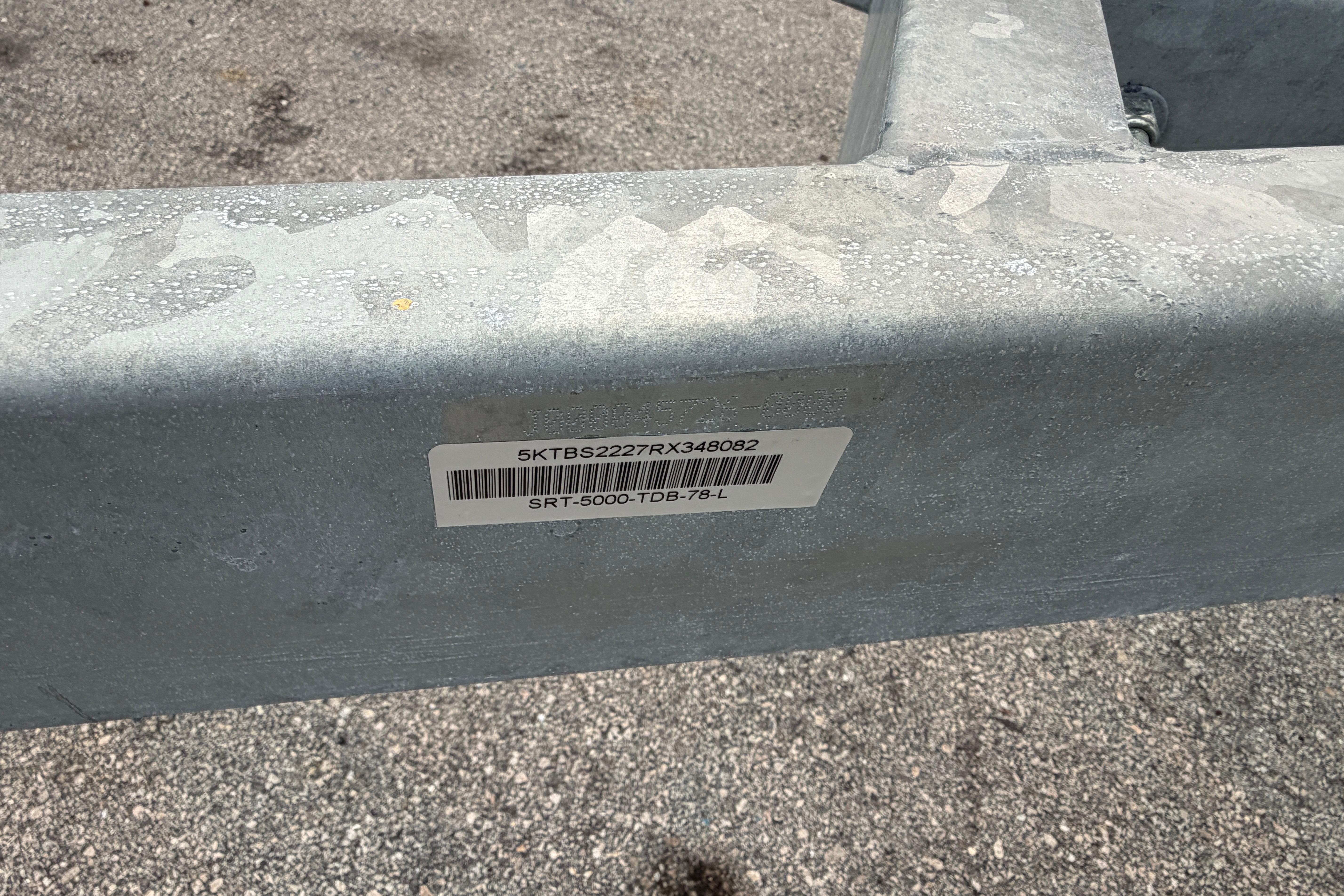 Metal frame with barcode label, model SRT5000, year 2024, on textured ground.