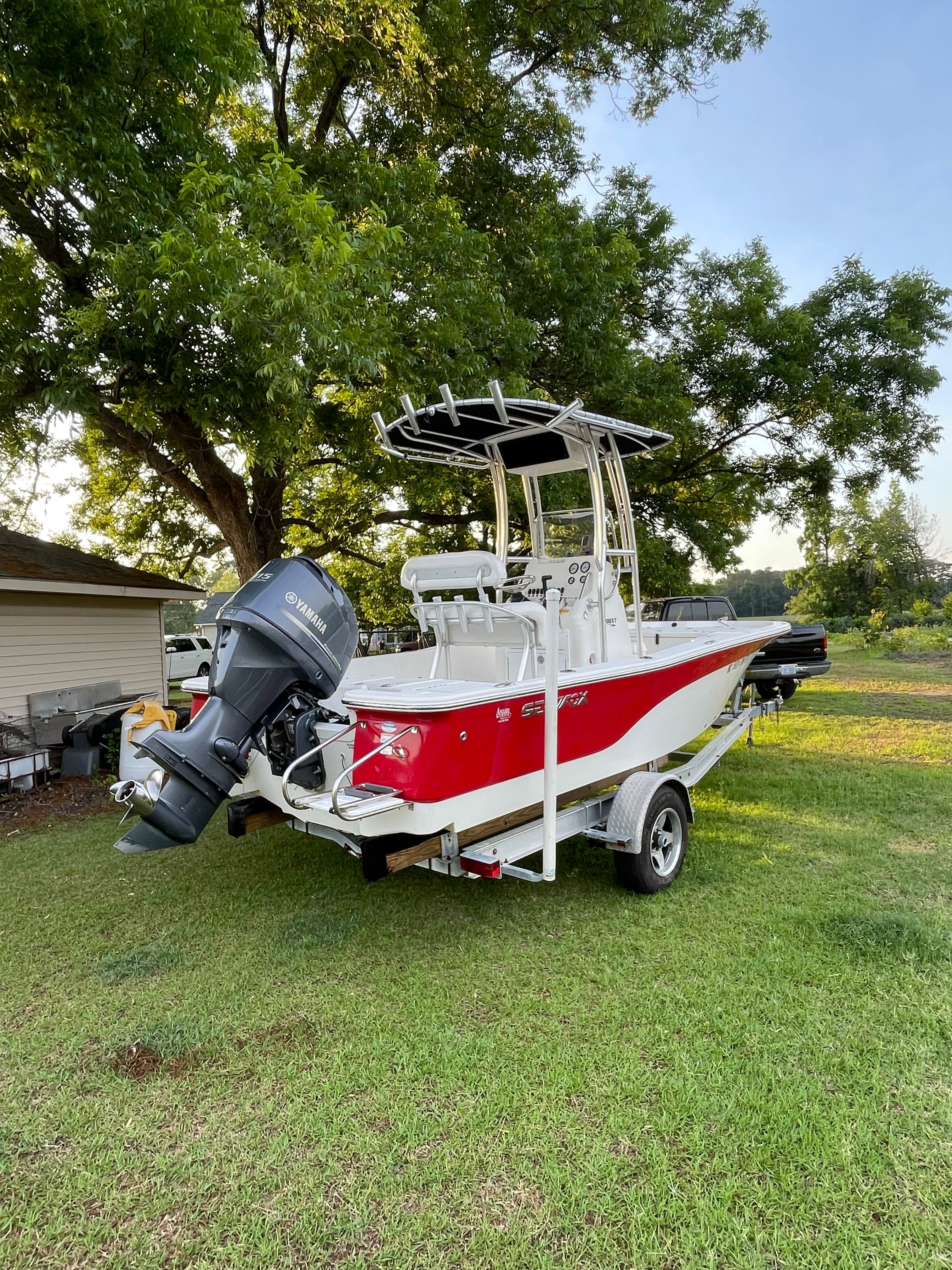A red 2012 Sea Fox 200XT boat on a trailer, set on grass.