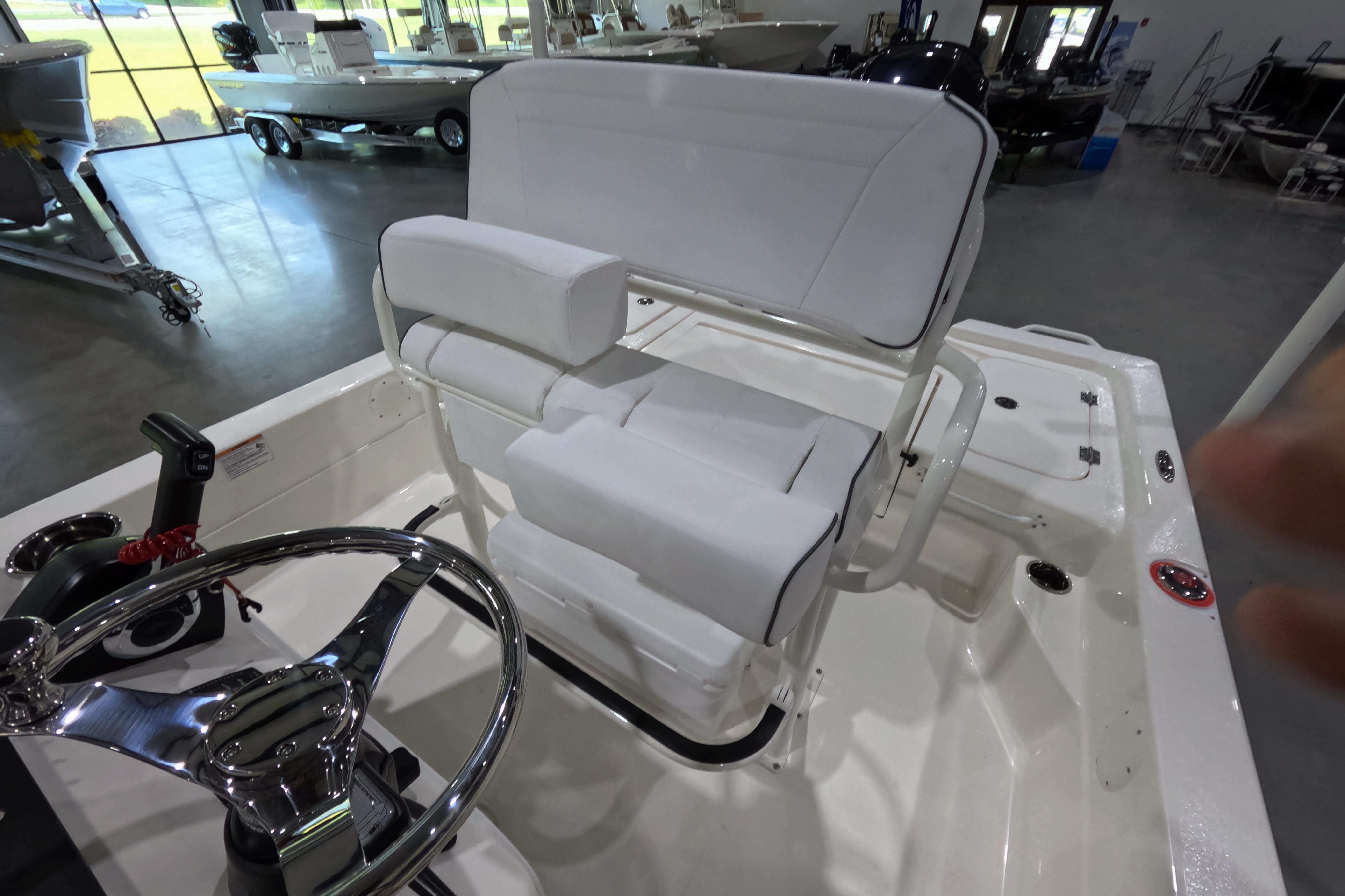 2026 Skeeter boat interior with white cushioned seating and steering wheel in showroom.