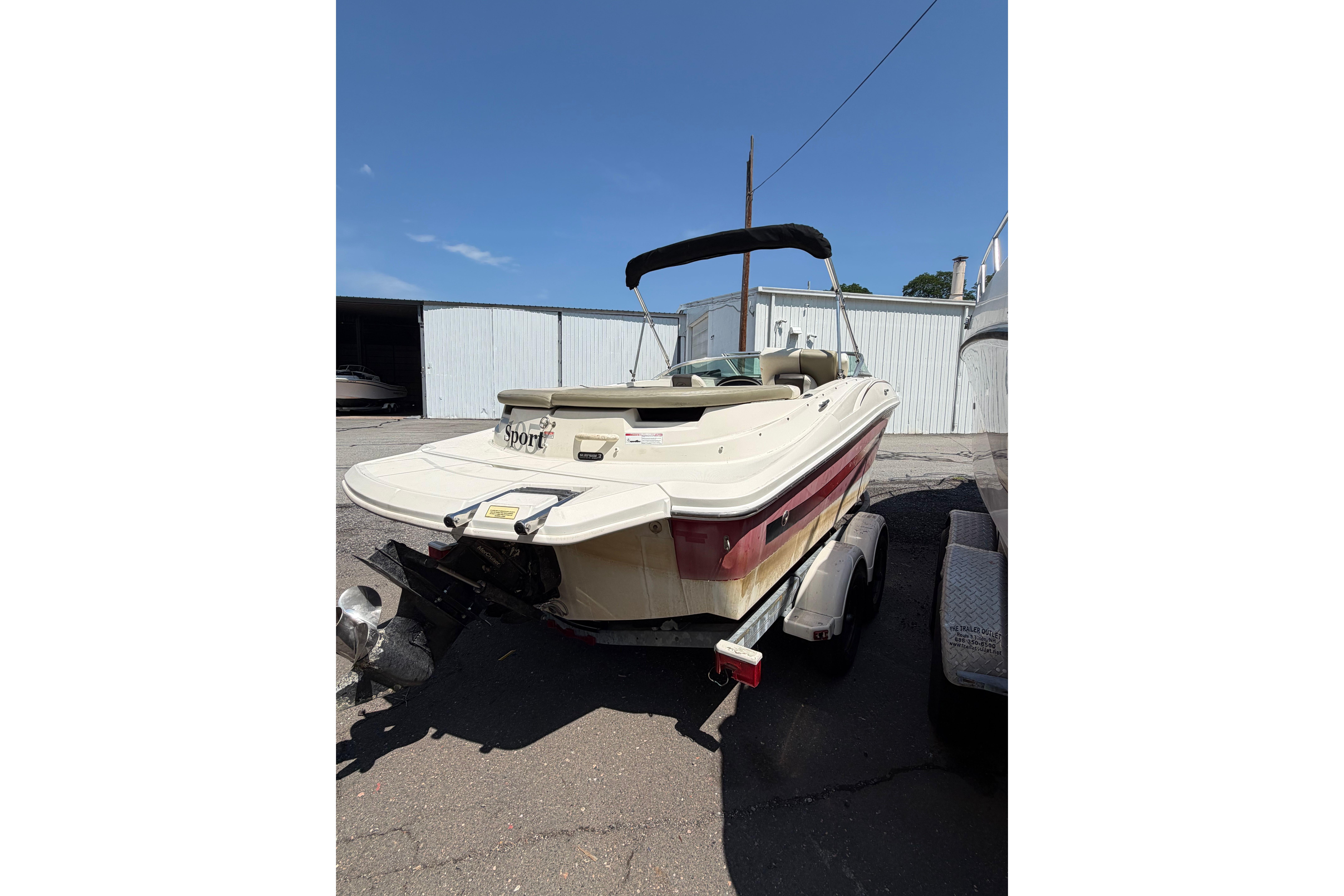 2006 Sea Ray 195 Sport boat on trailer, parked outdoors under clear blue sky.