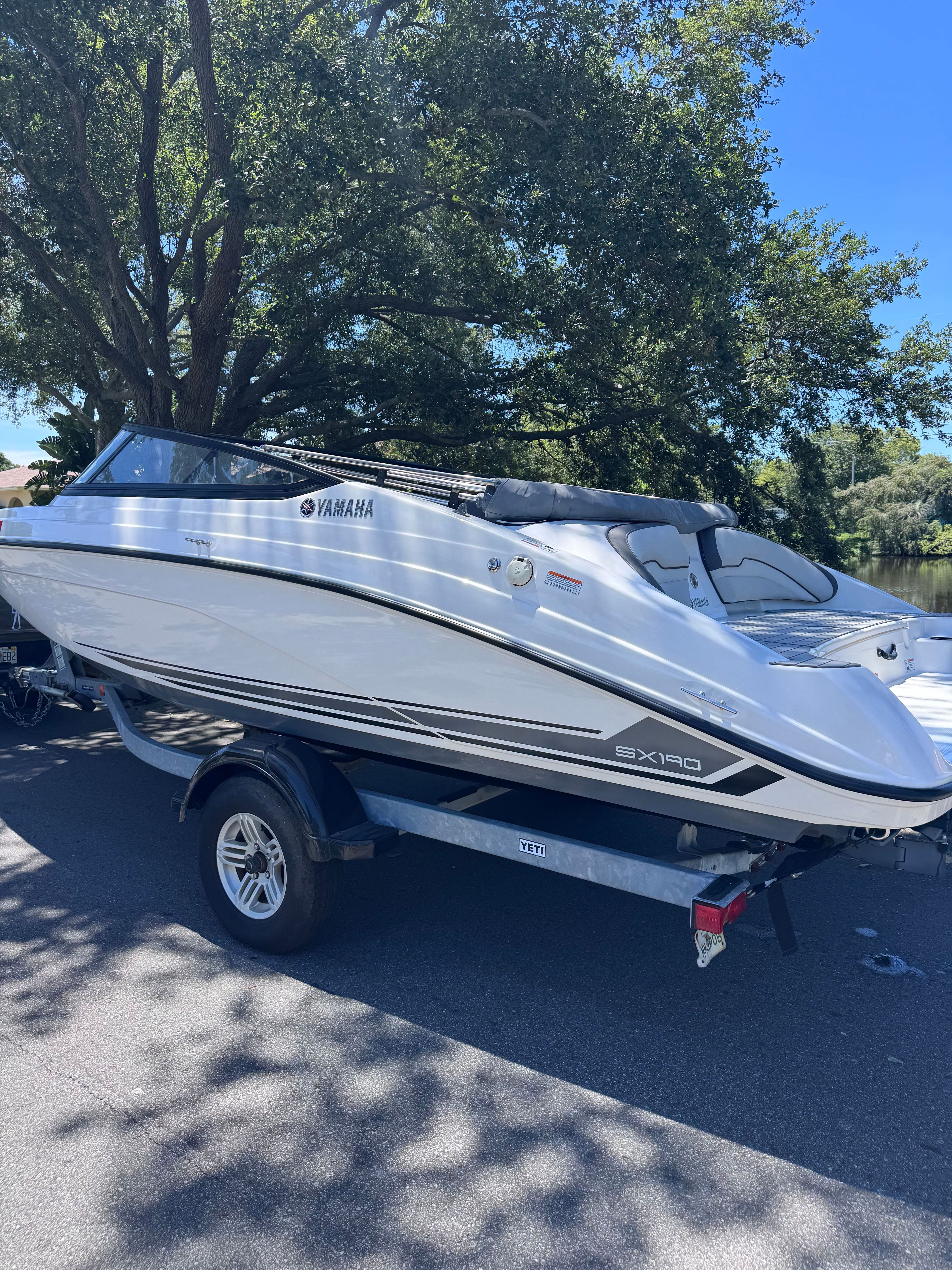 2020 Yamaha SX190 boat on trailer under trees.
