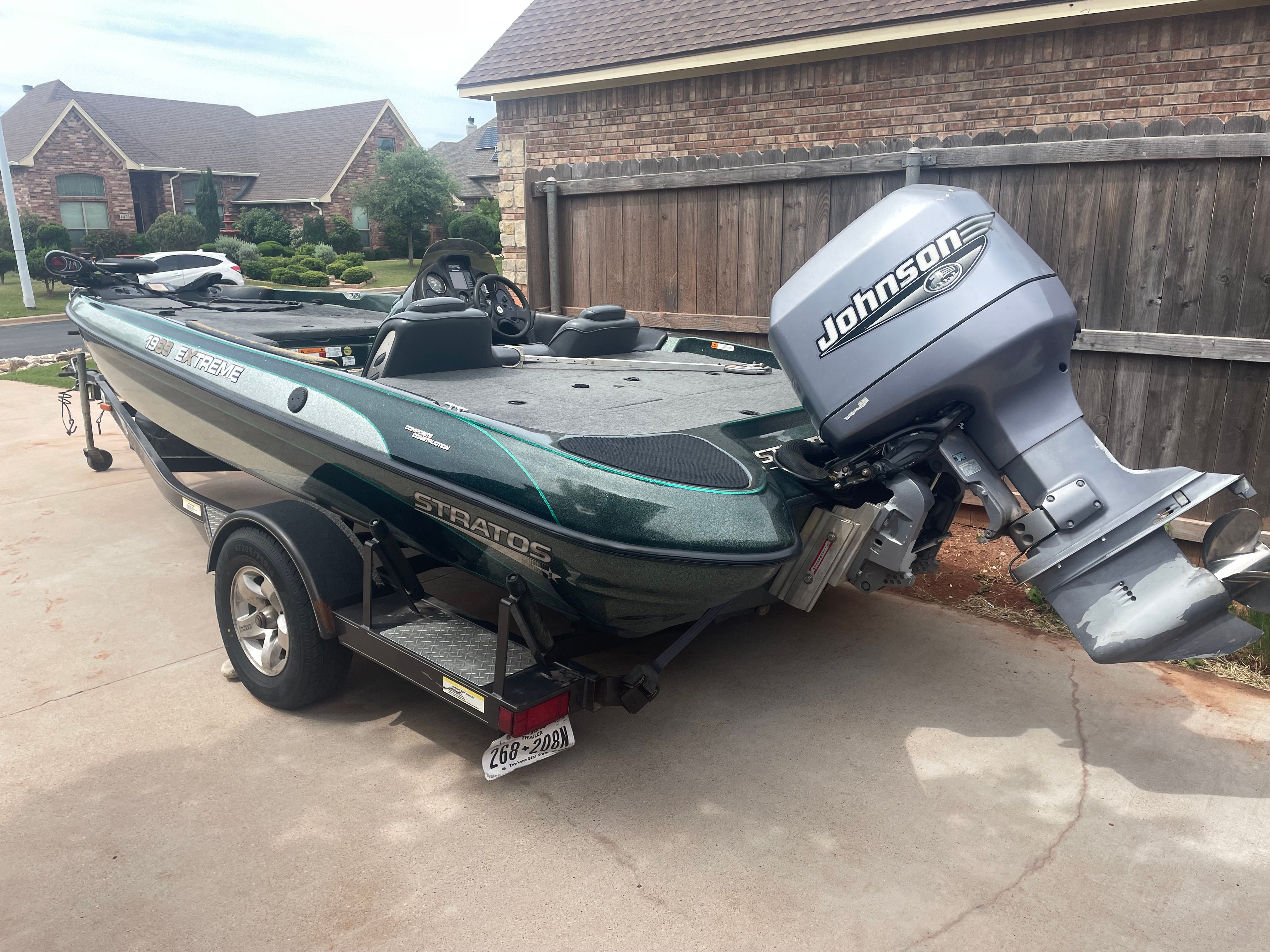 A green 2000 Stratos 19 SS boat with a Johnson outboard motor on a trailer.