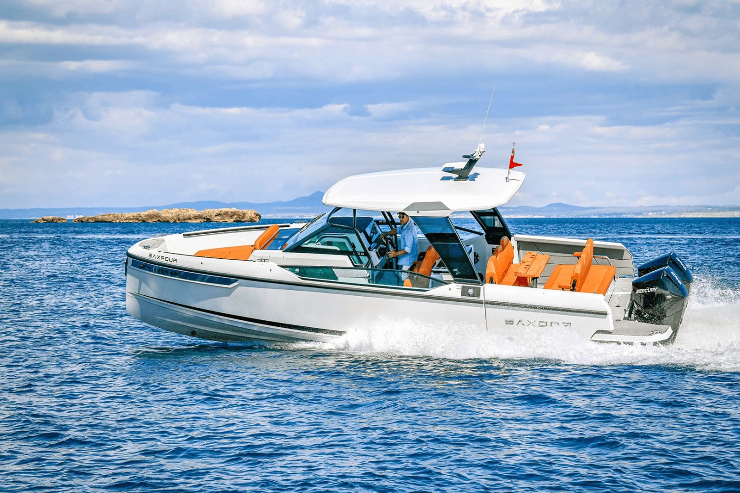 A modern motorboat with orange seats cruising on the sea.