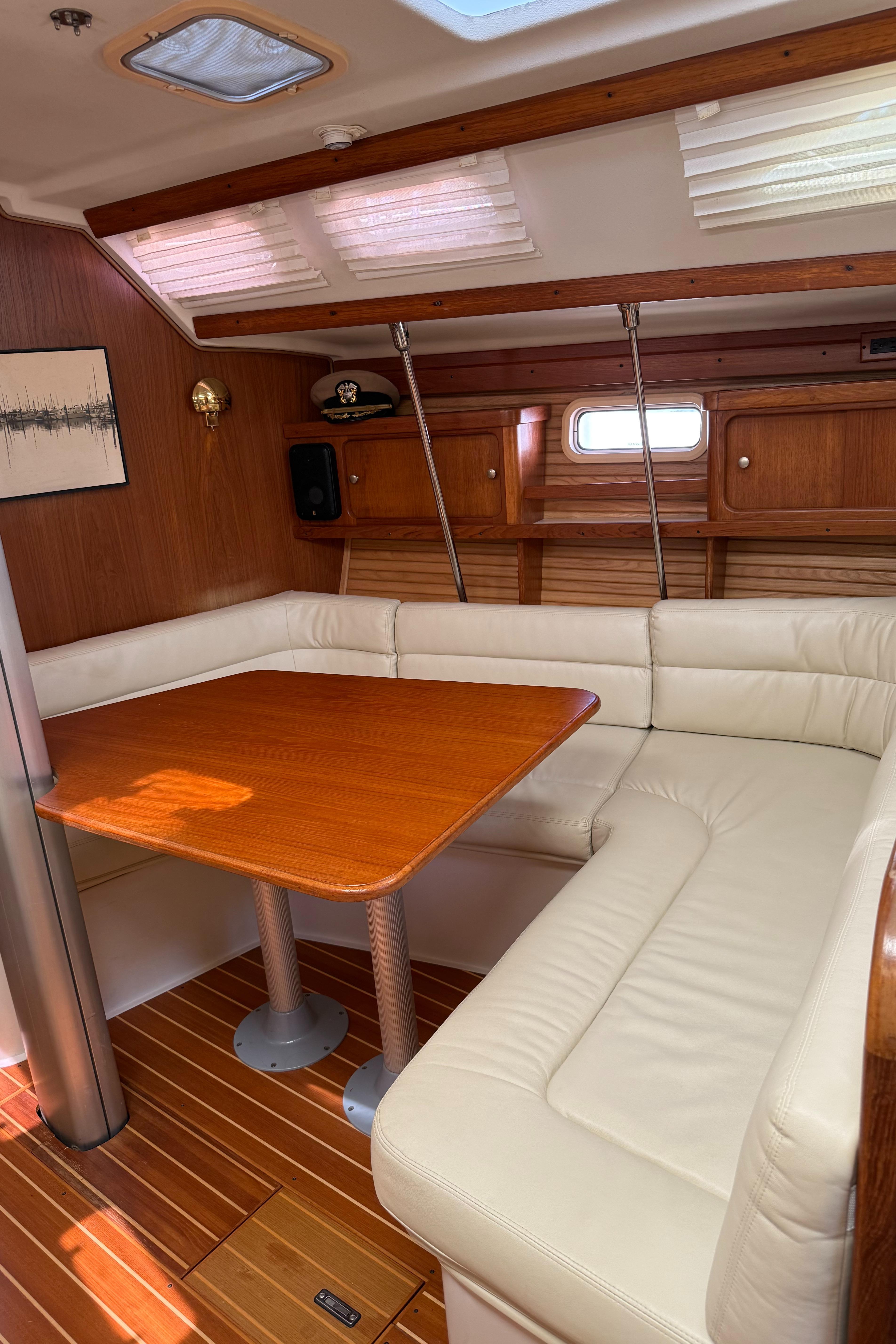 Interior of 1998 Catalina 400 sailboat with wooden table and white leather seating.