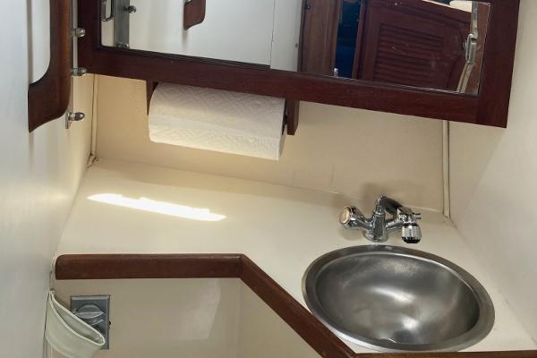 1989 Catalina 30 yacht bathroom with sink, mirror, and paper towel holder.