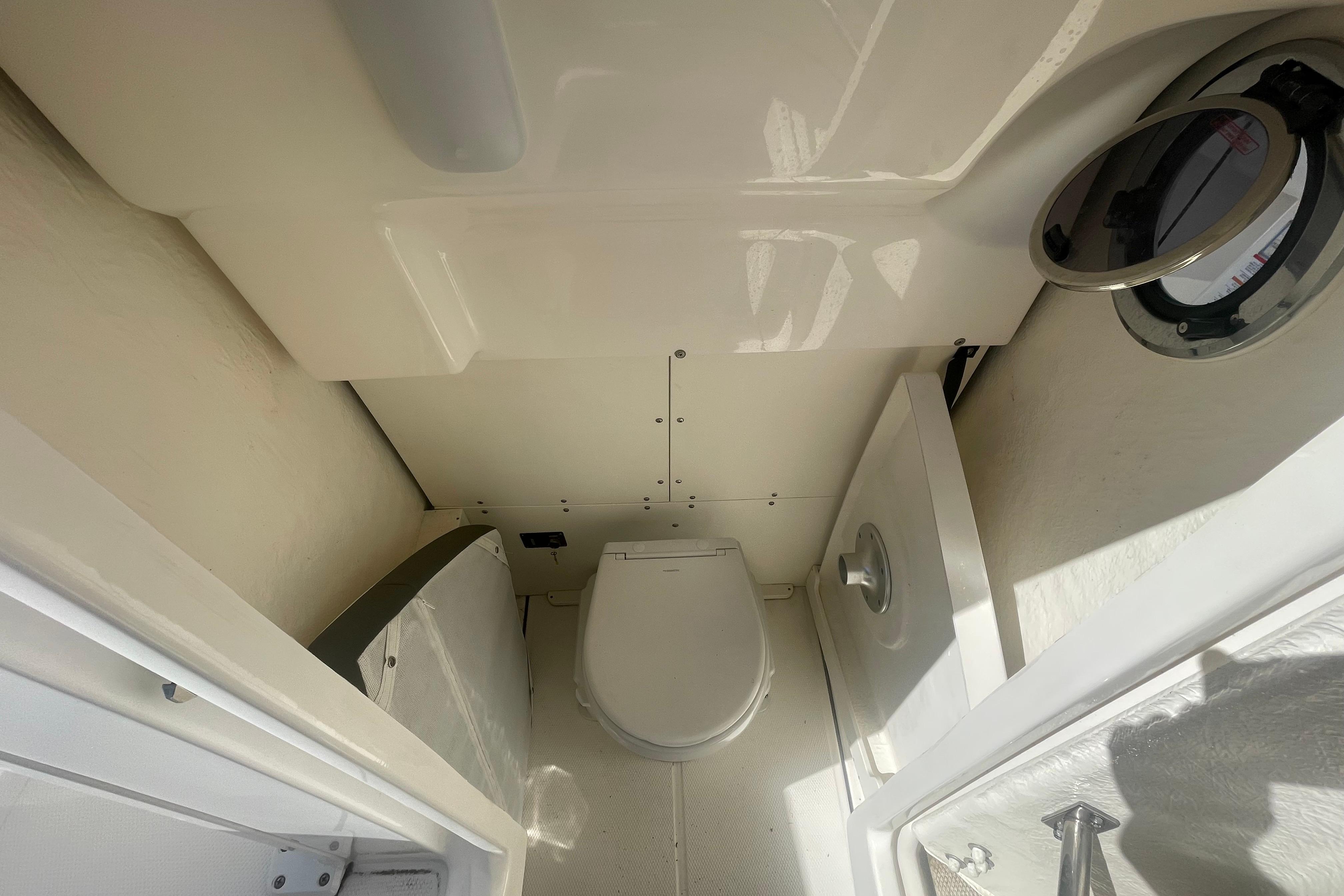 2023 Robalo R270 Center Console boat interior with compact marine toilet and porthole.